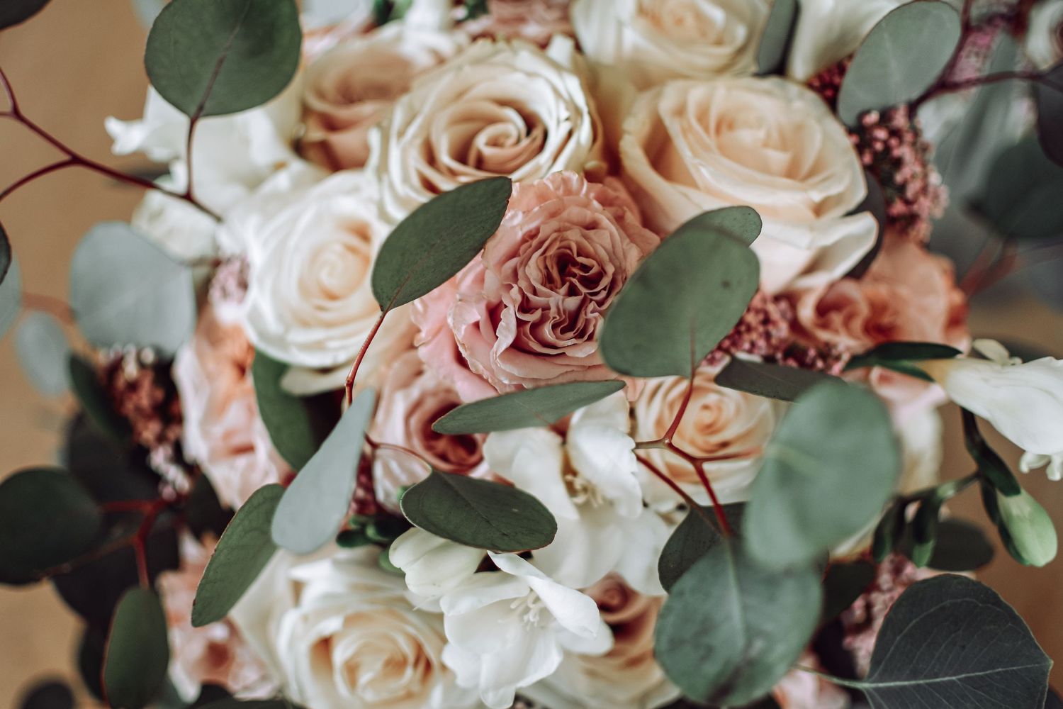 A romantic wedding bouquet featuring blush pink roses and fresh eucalyptus arranged in a delicate design.