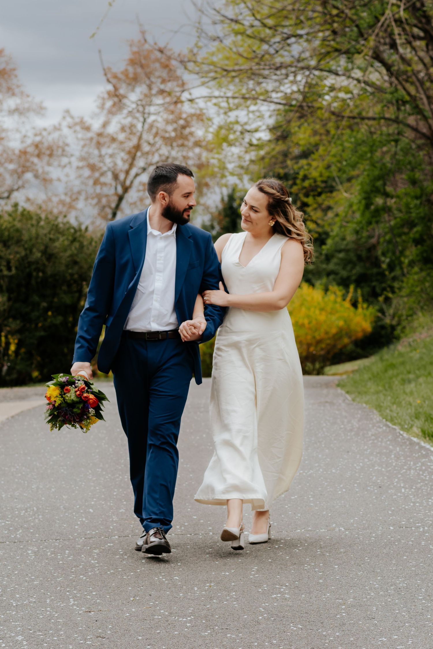 A romantic wedding photoshoot sequence shows a couple walking playfully on a gravel path surrounded by autumn trees.