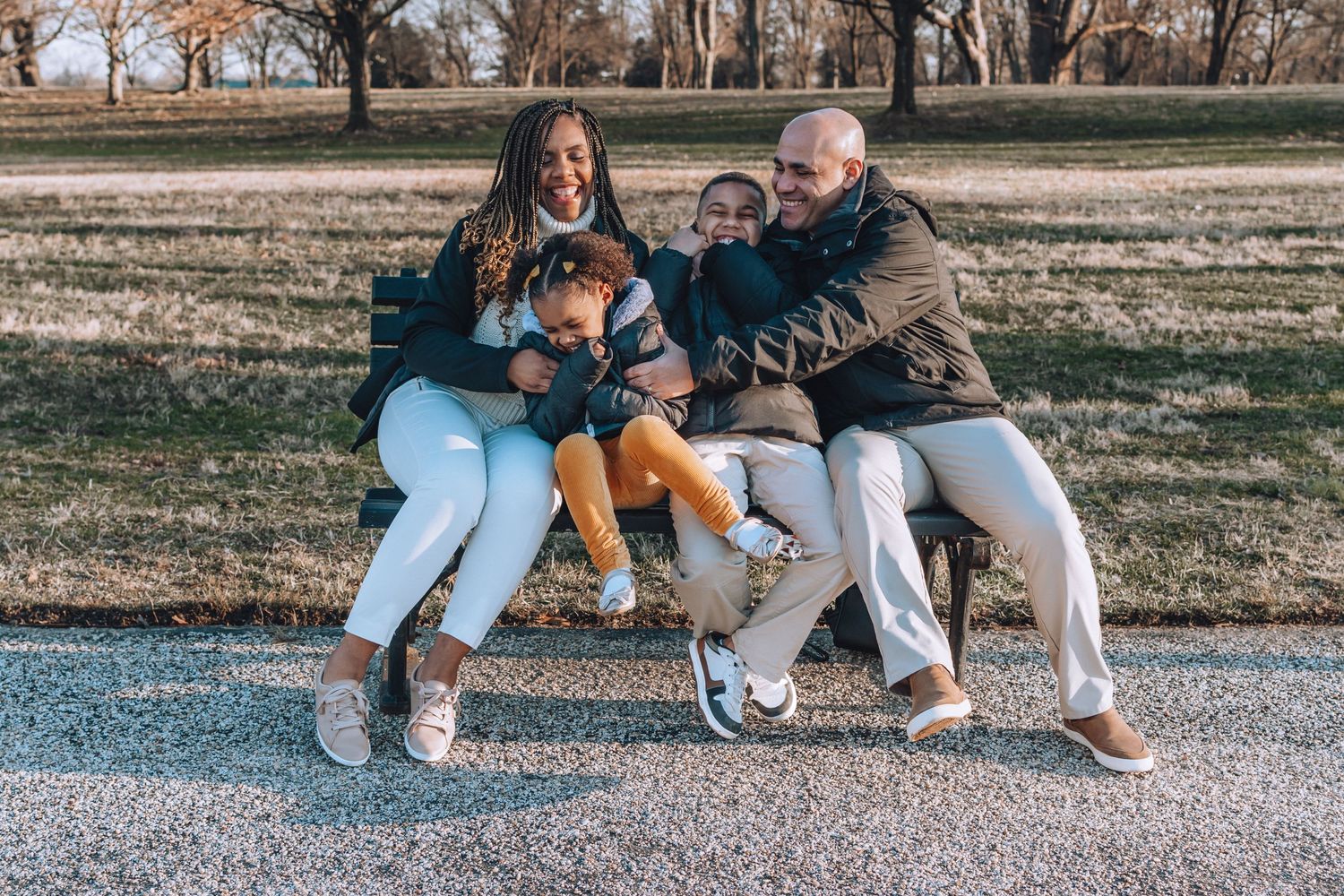 A group shares laughter while sitting together on a park bench on an autumn afternoon.