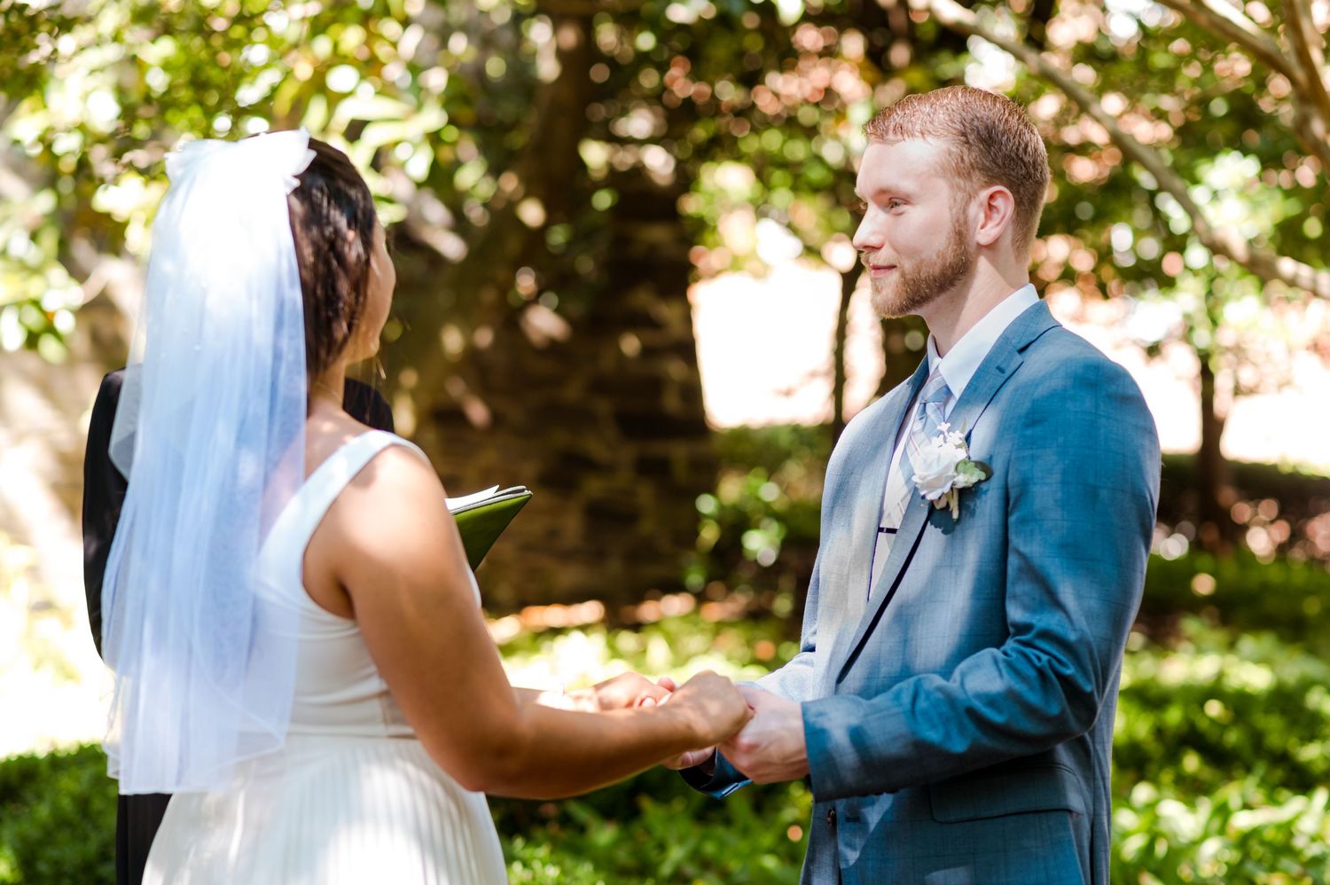 Intimate outdoor wedding ceremony with couple exchanging vows in a garden setting.