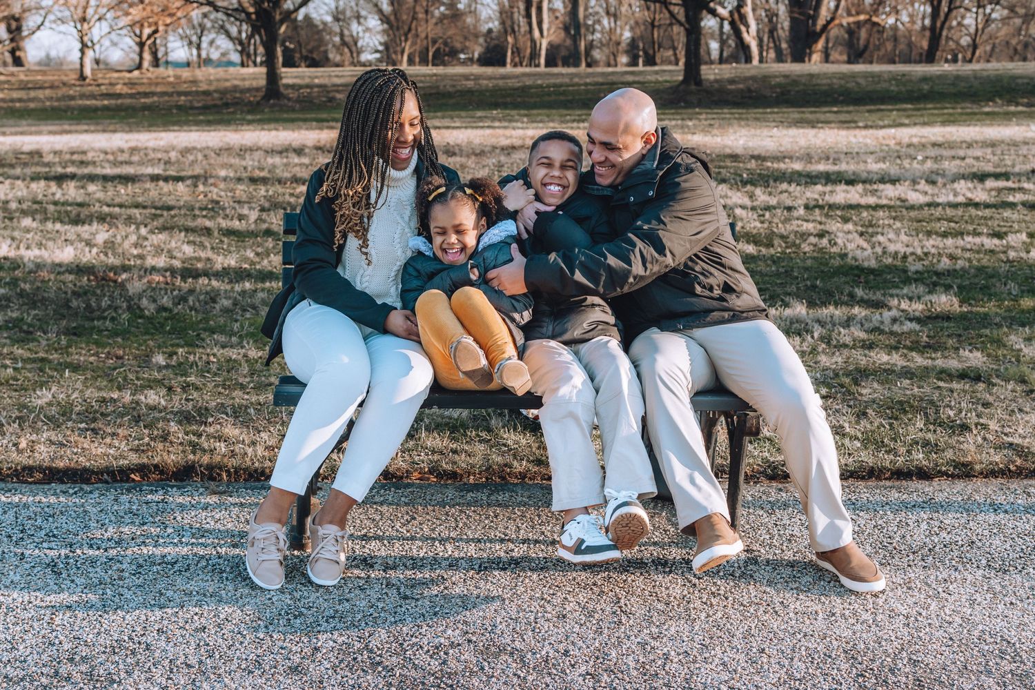 A group shares a laugh while sitting close together on a park bench.