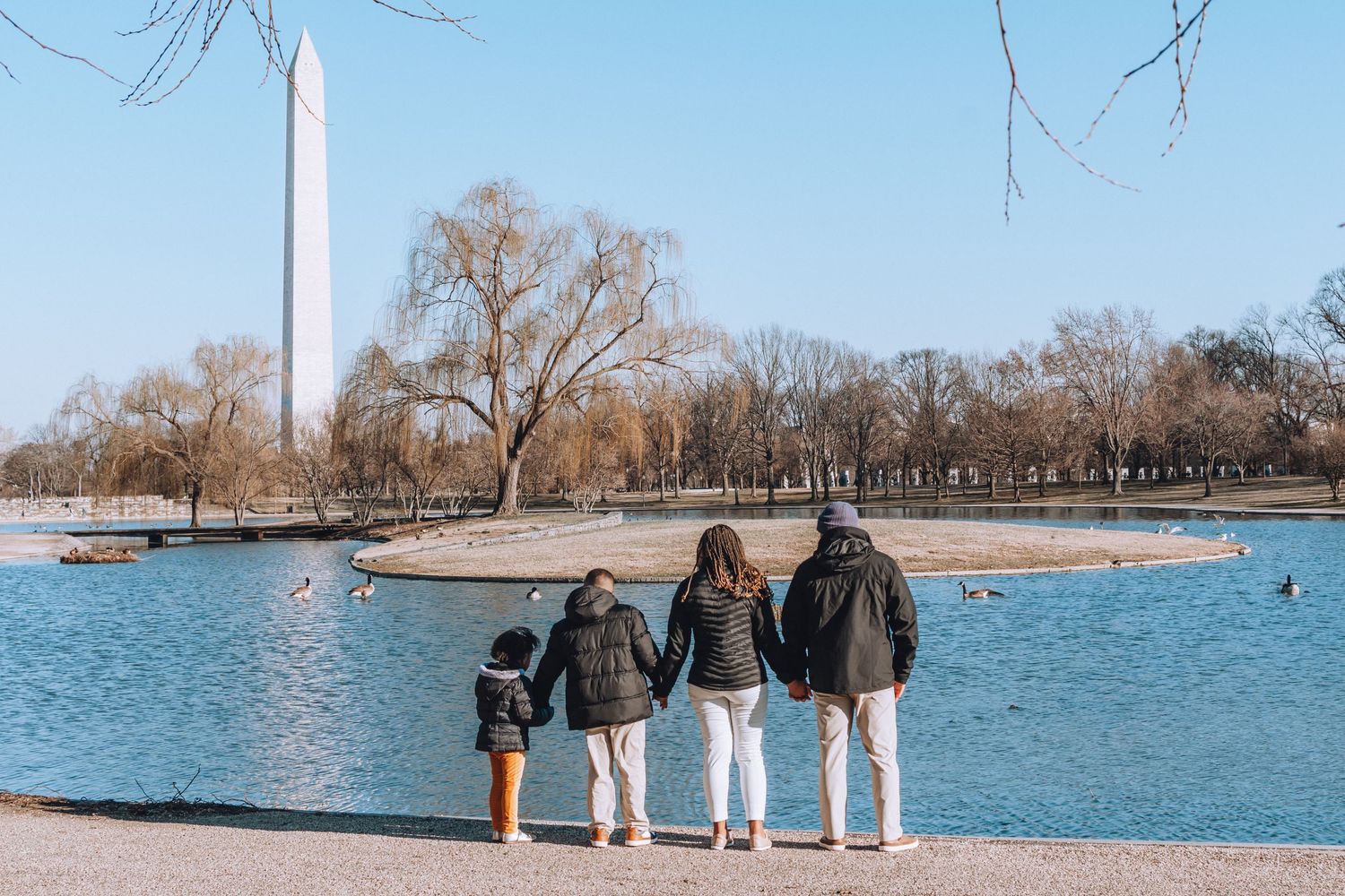 Family stands together looking at Washington Monument and reflecting pool.