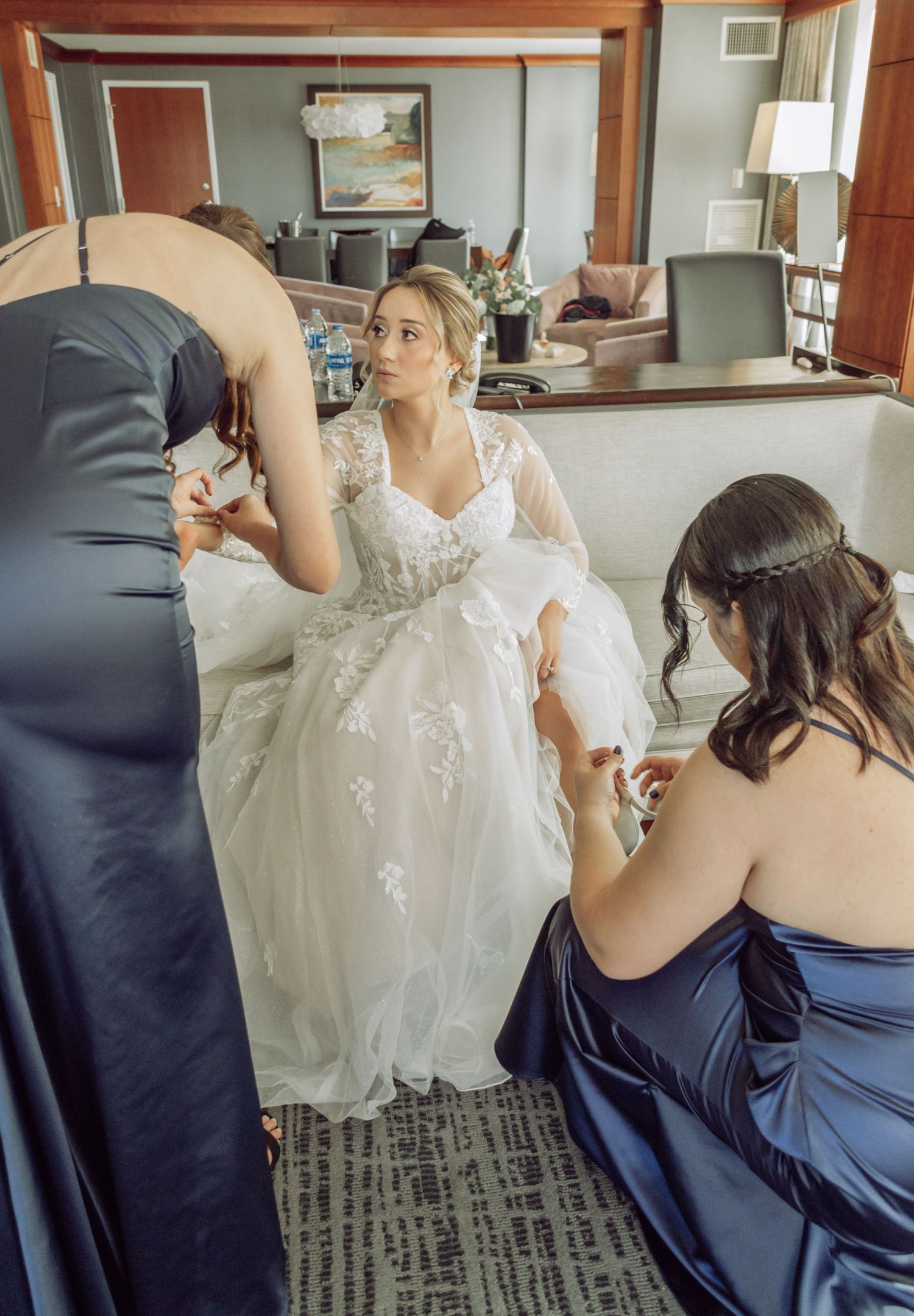 Four sequential photos showing a person in white dress getting help adjusting their gown from someone in navy blue attire.