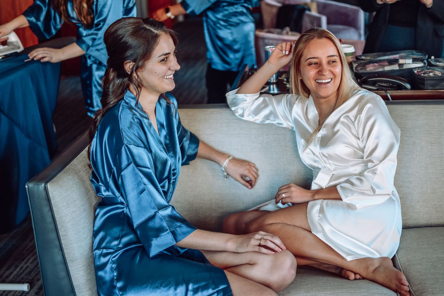 Two people in silk robes relax on a couch while having an animated conversation together.