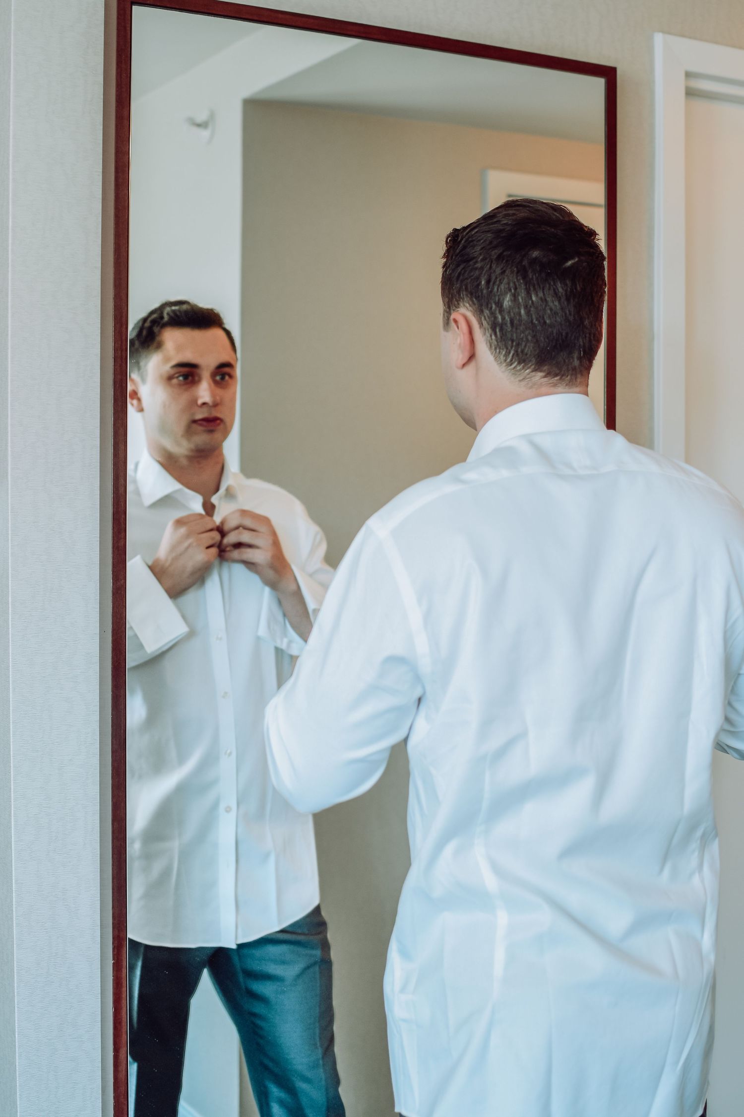 A collage showing multiple views of someone in a white shirt and green pants looking into a bathroom mirror.