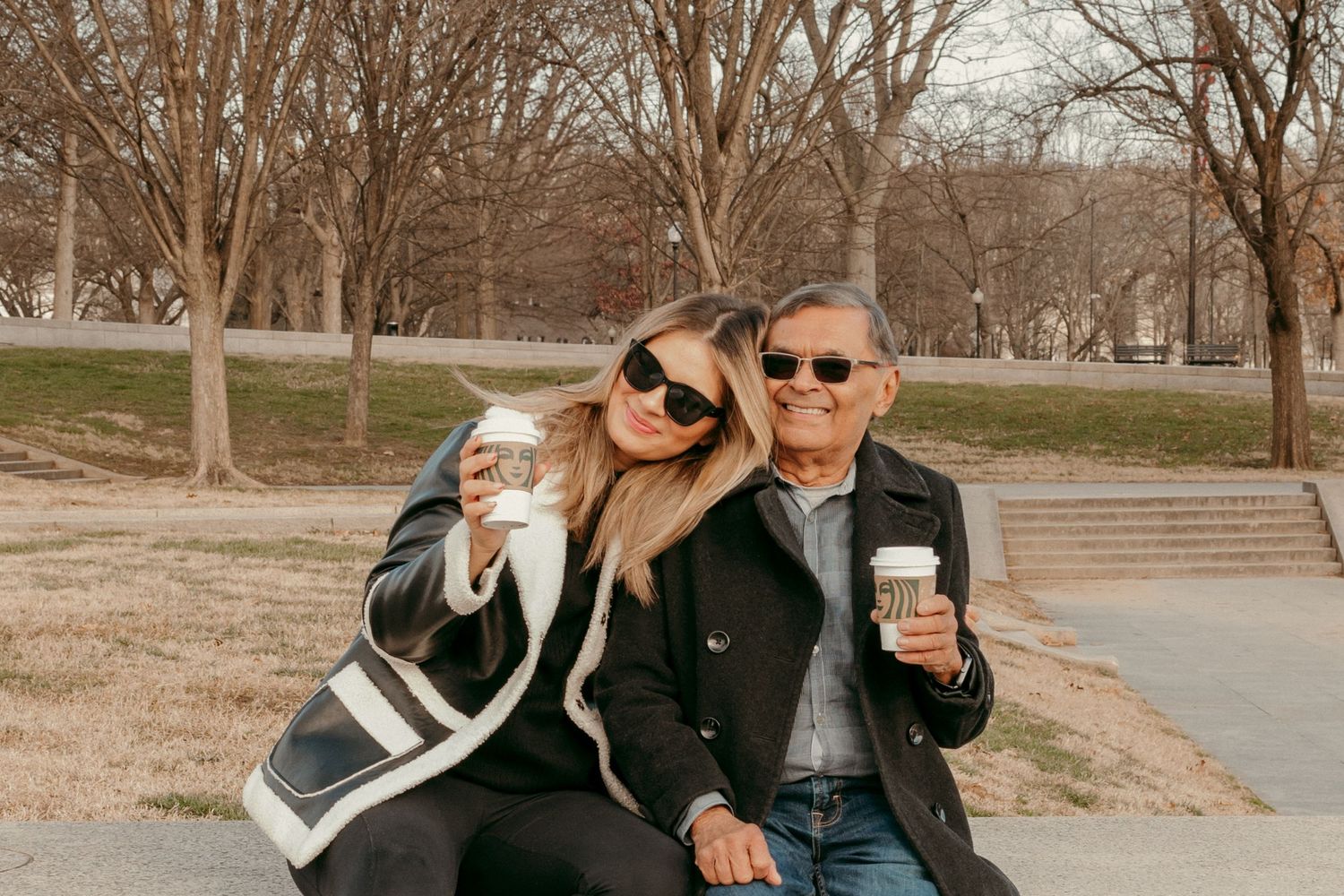 Two people sharing coffee and smiles while sitting outdoors on a fall day.