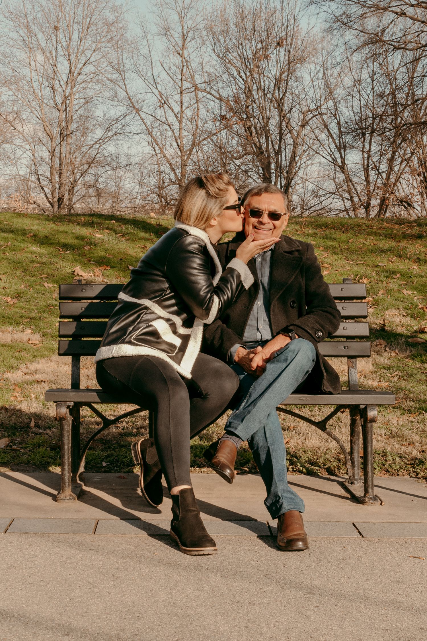 Two people sharing intimate moment while sitting together on park bench.