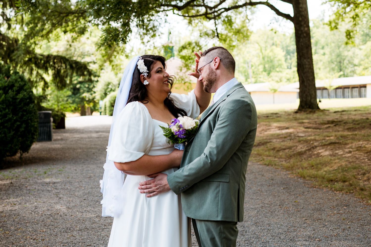 A couple shares tender moments together in a sun-dappled park setting during a wedding photo session.