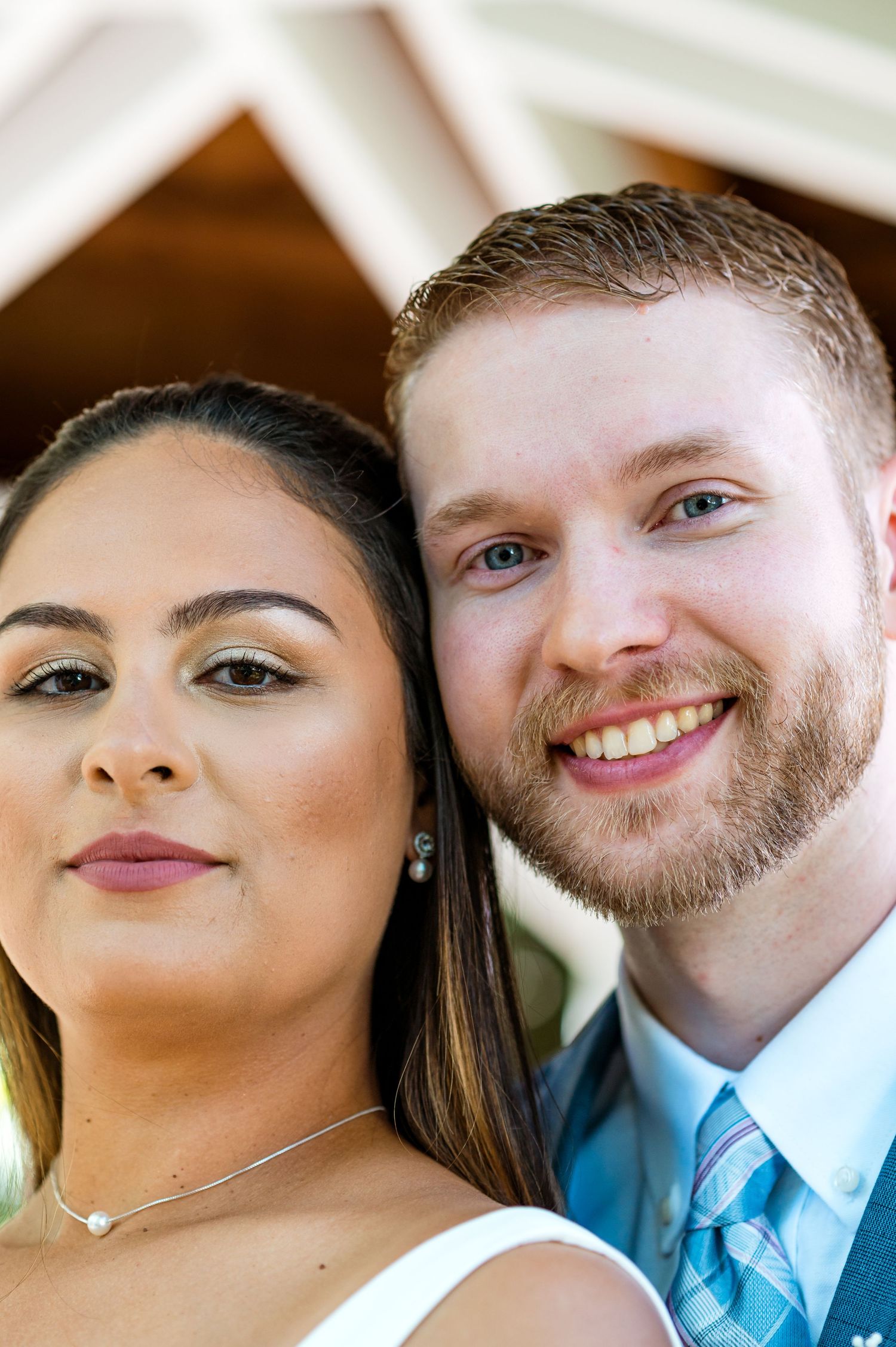 Close-up wedding portrait showing couple in white gazebo with natural lighting.
