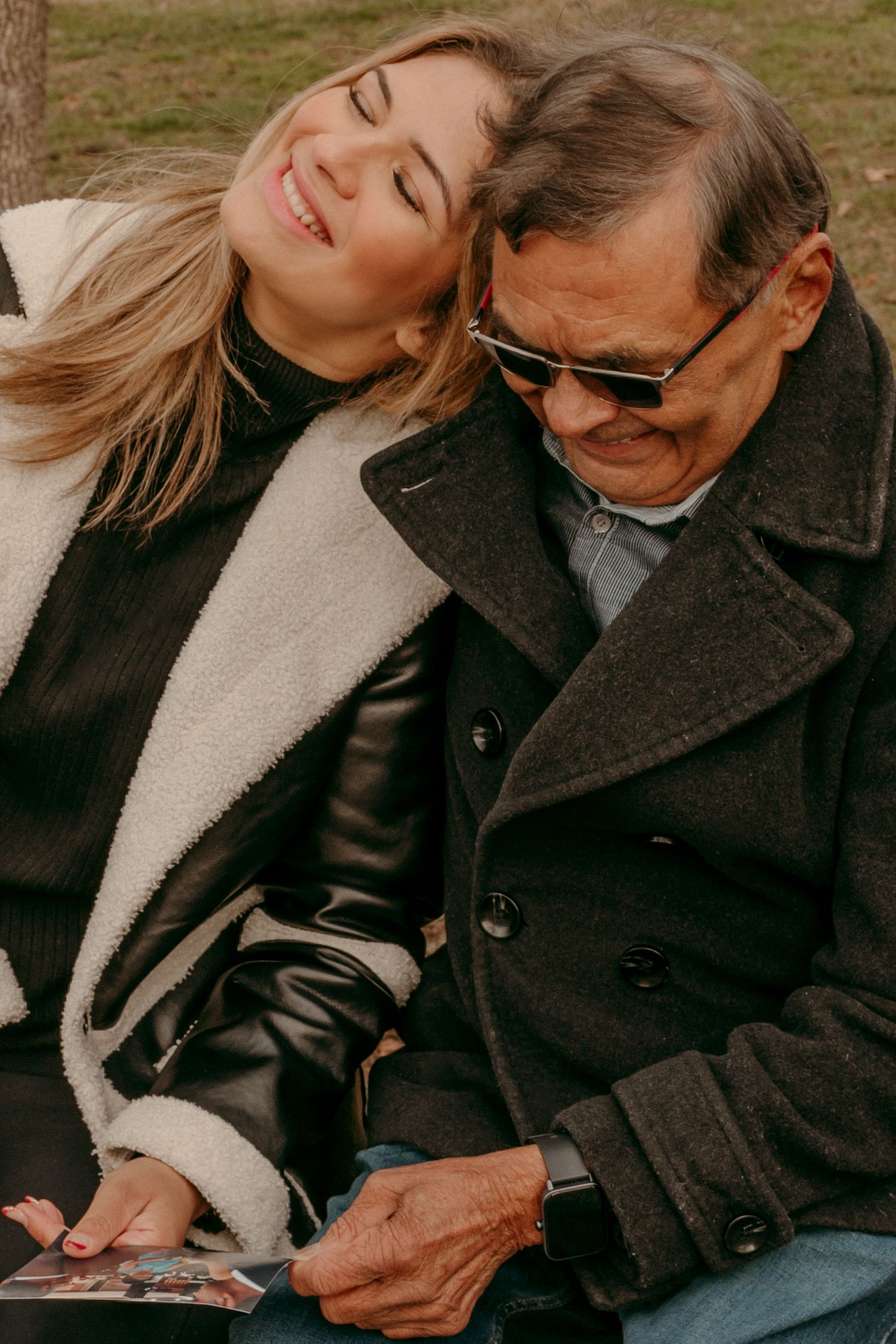 Two people share an intimate moment outdoors while wearing winter coats.