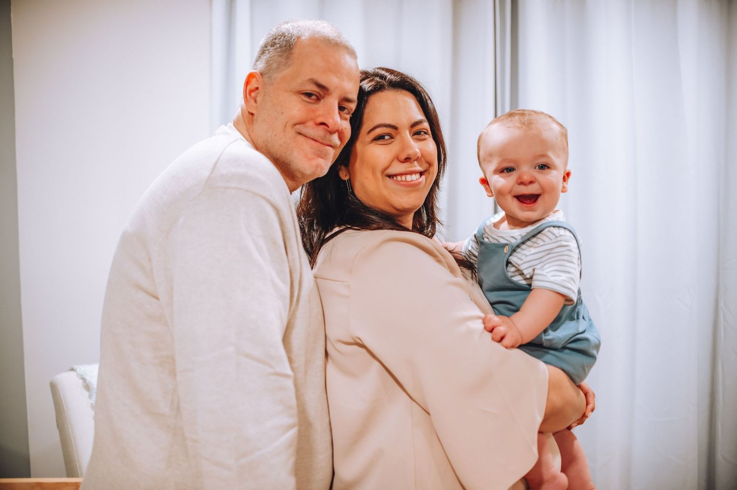 Happy family portrait in a modern nursery with natural lighting and neutral decor.