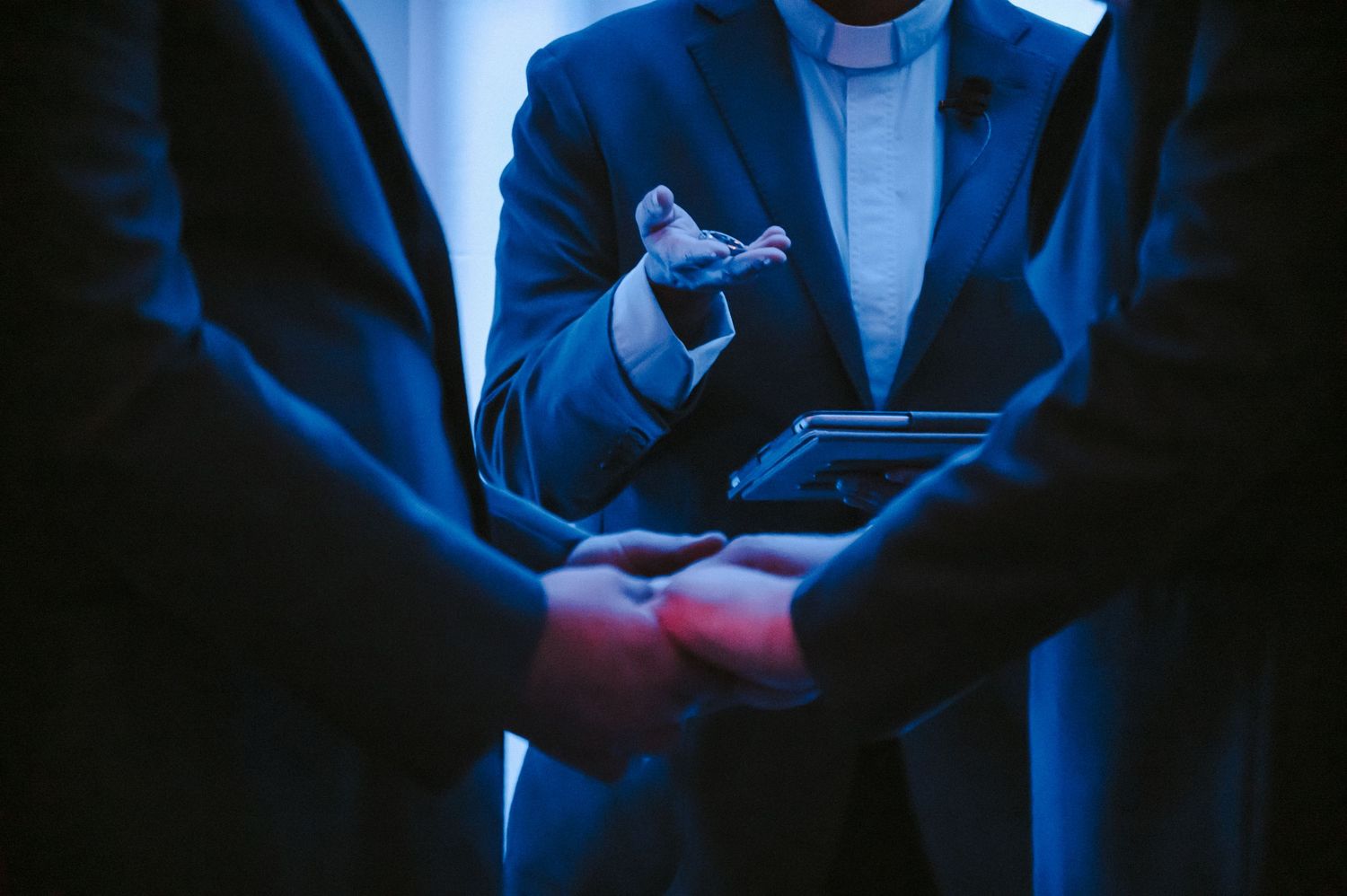 Someone checks their mobile phone in dark lighting while wearing a blue suit and white shirt.