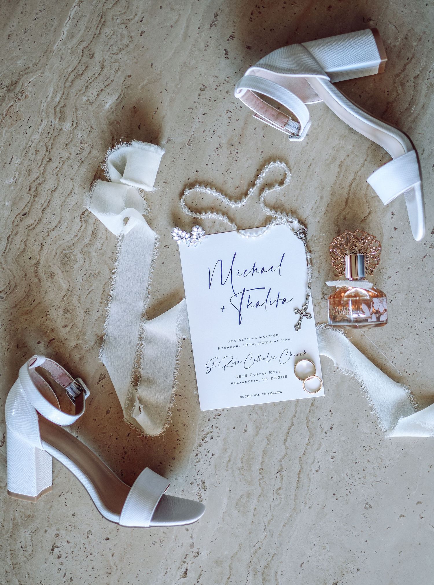 Elegant white wedding invitations with torn edges and calligraphy text arranged artistically on a textured surface.