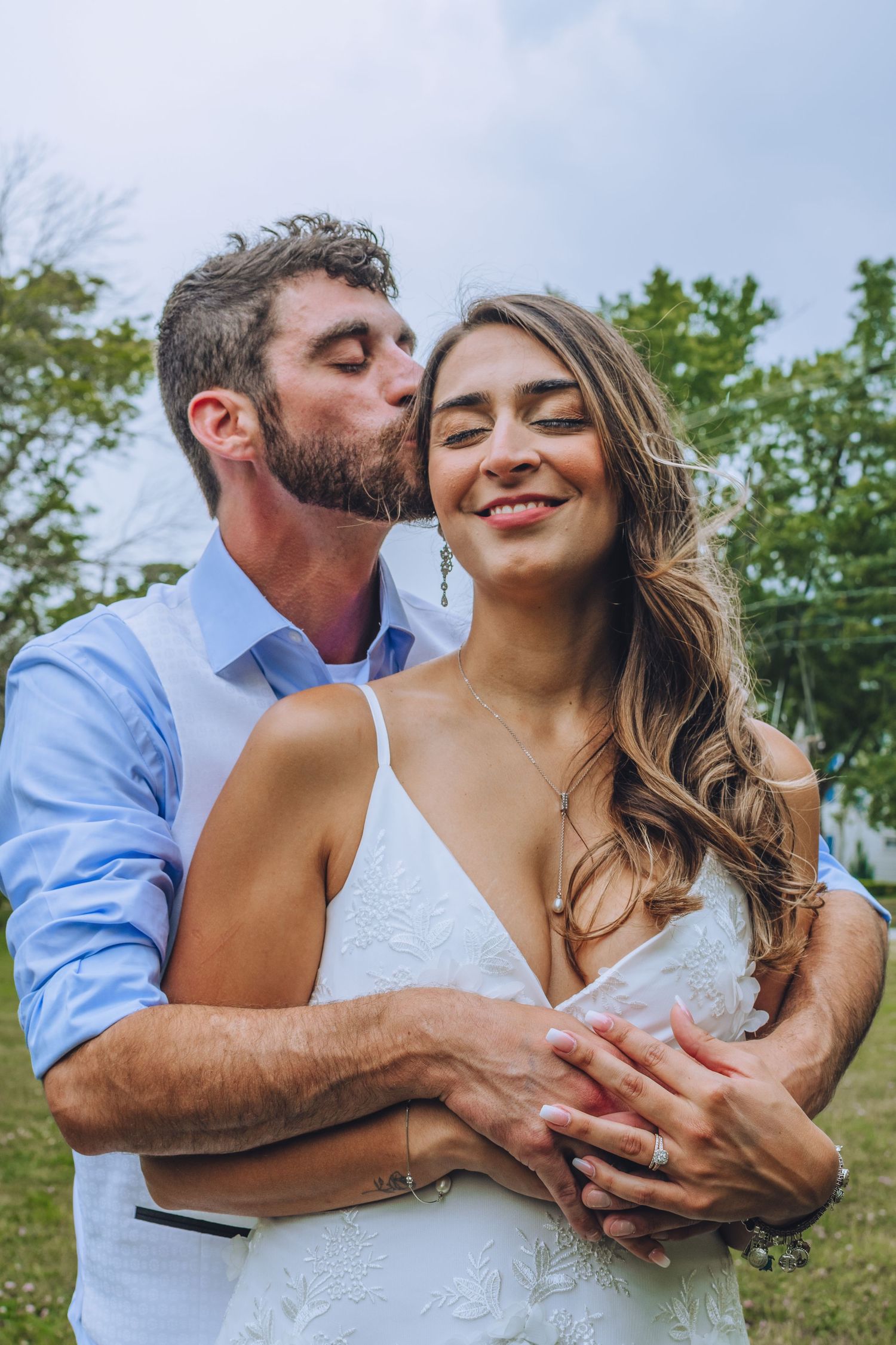 Romantic outdoor portrait of couple embracing in casual wedding attire.