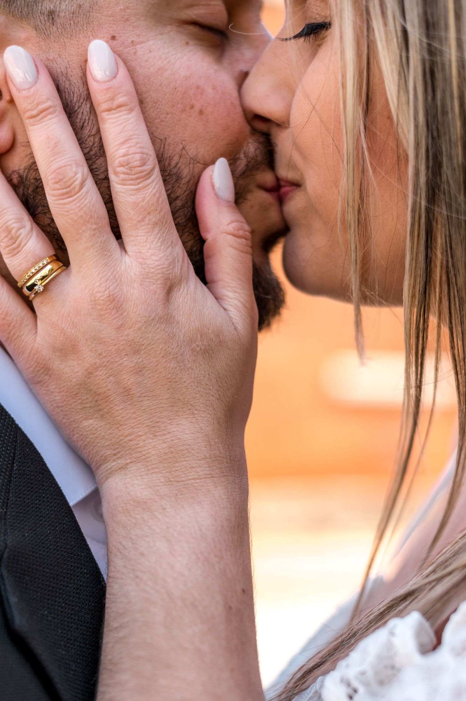 Close-up shot of a romantic kiss with a gold ring visible on the hand during an intimate moment.