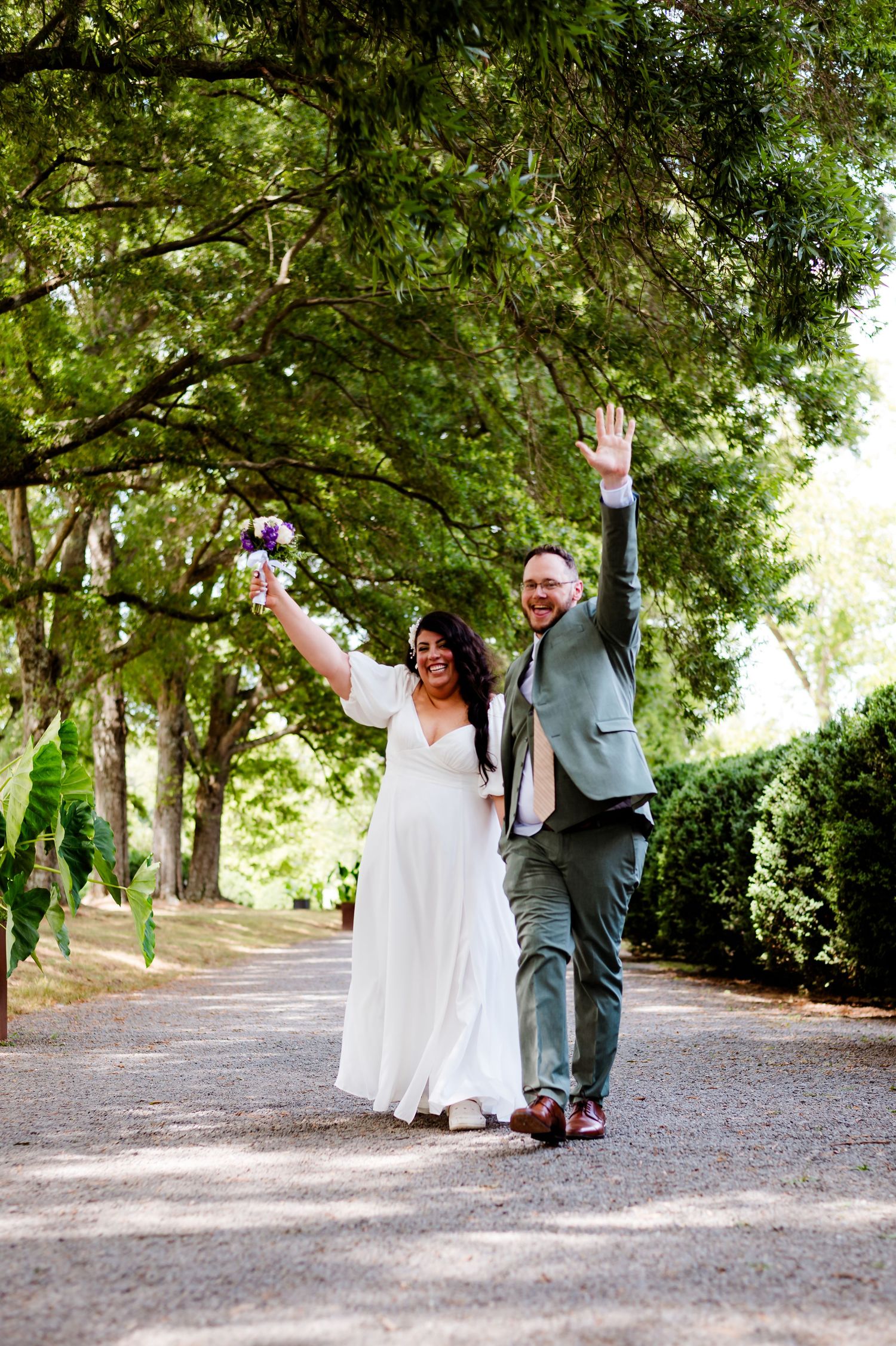 Happy couple celebrating with raised arms on a scenic garden pathway.
