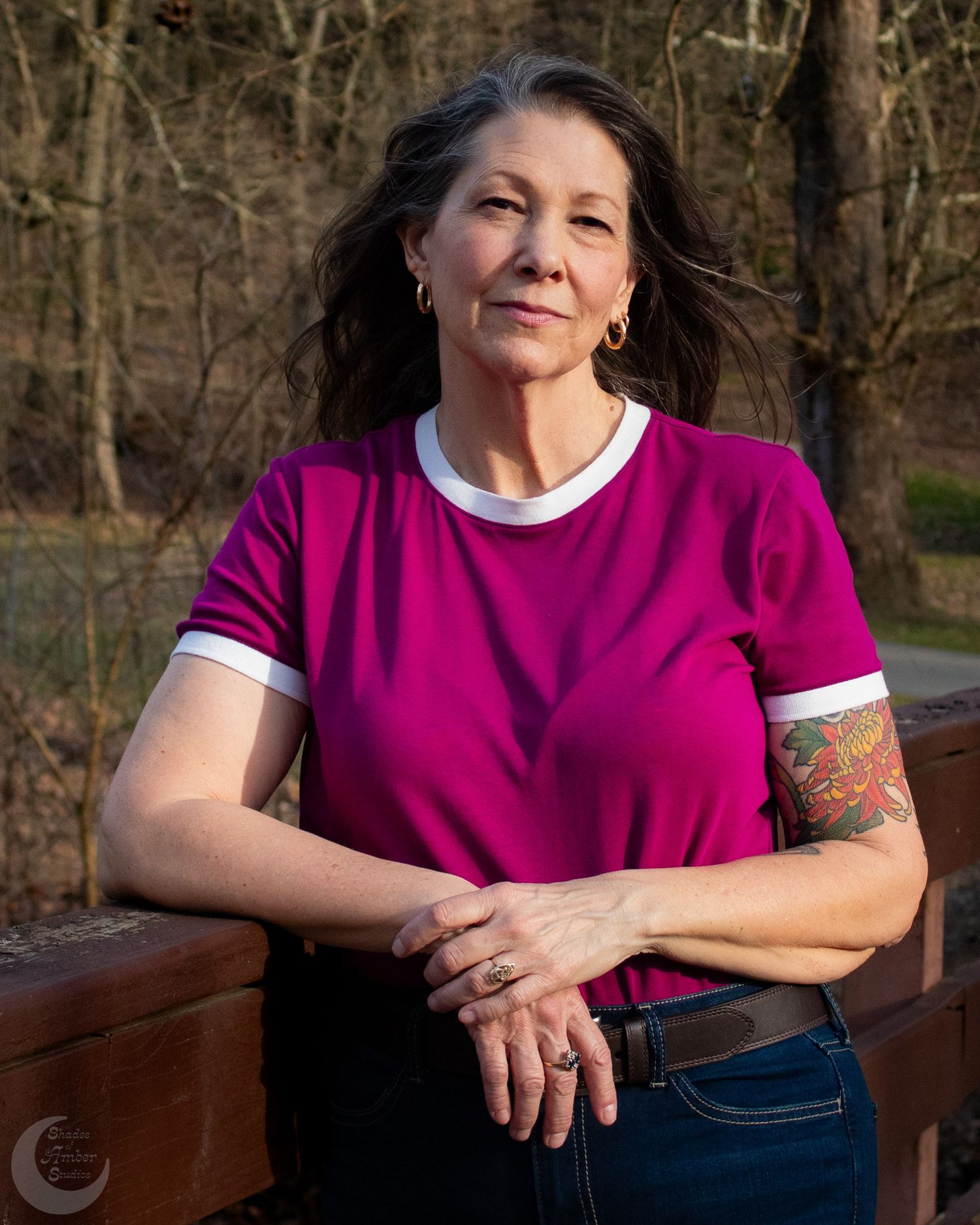 Outdoor portrait in magenta shirt showing relaxed pose against natural background.