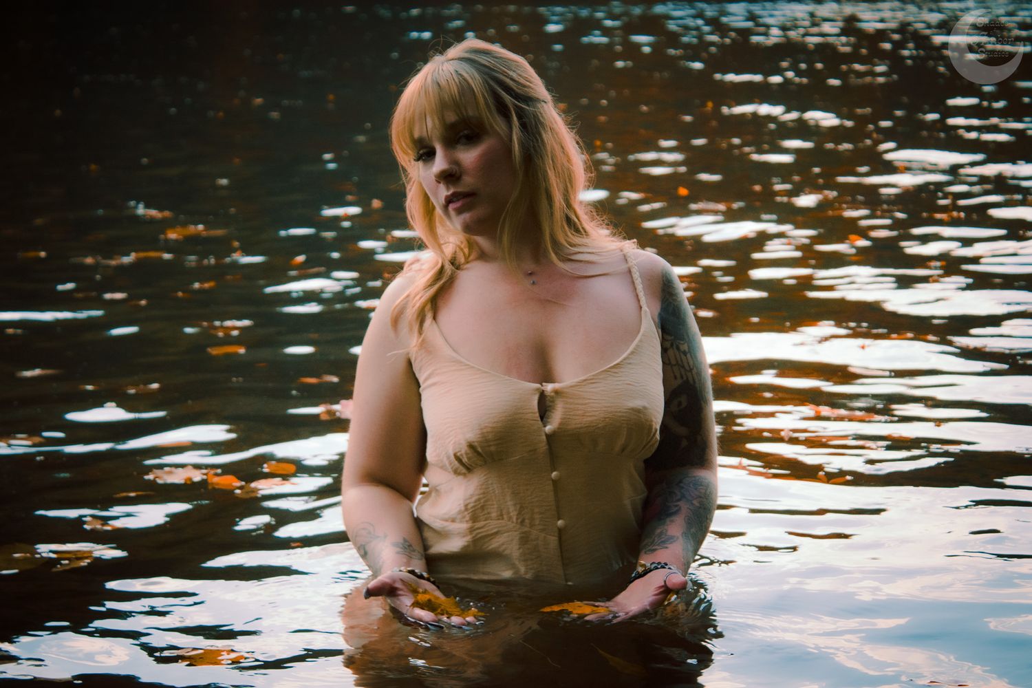 Person in vintage-style corset standing in lake water with autumn reflections.