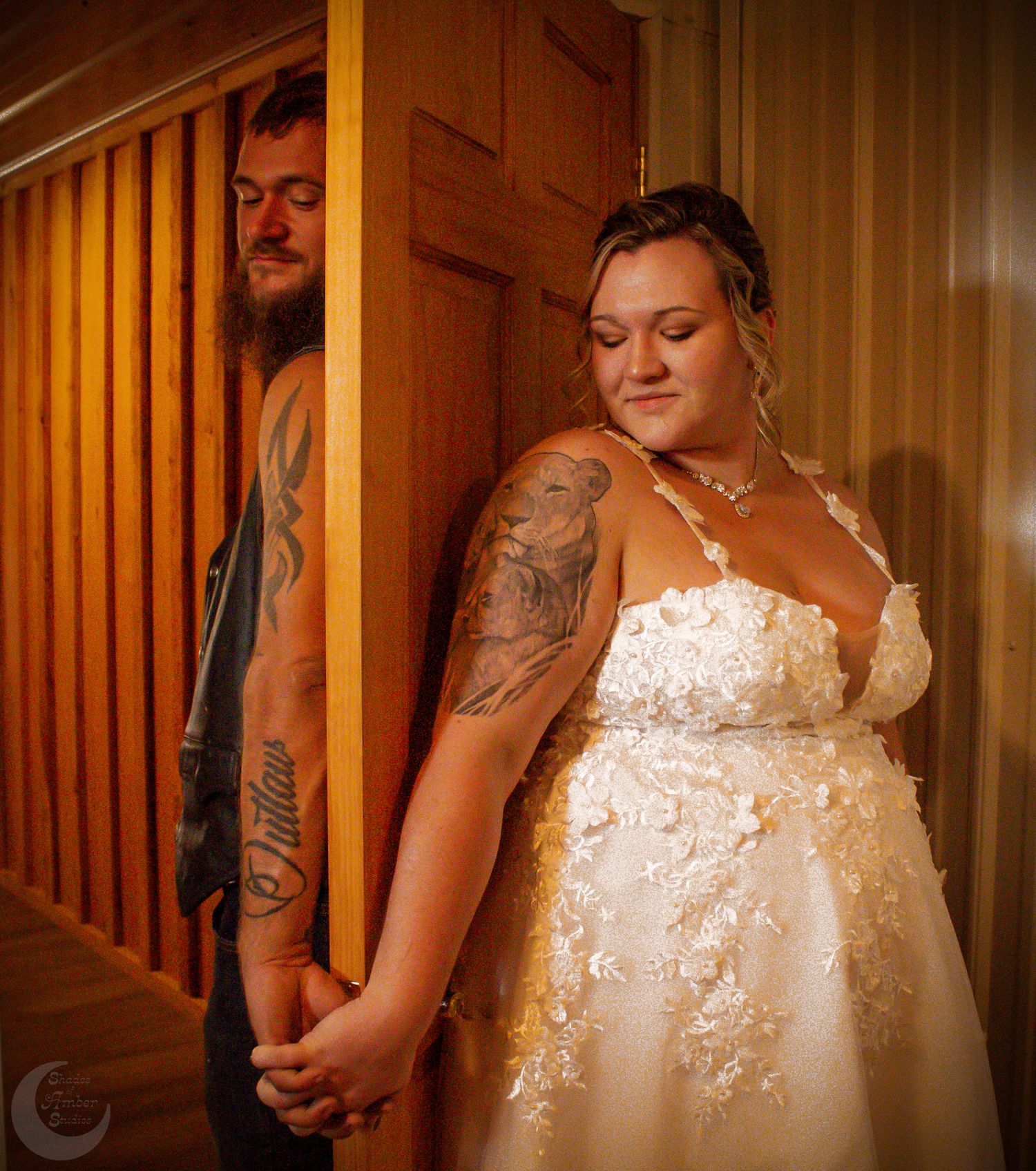 A creative wedding portrait through wooden slats showing a couple holding hands.