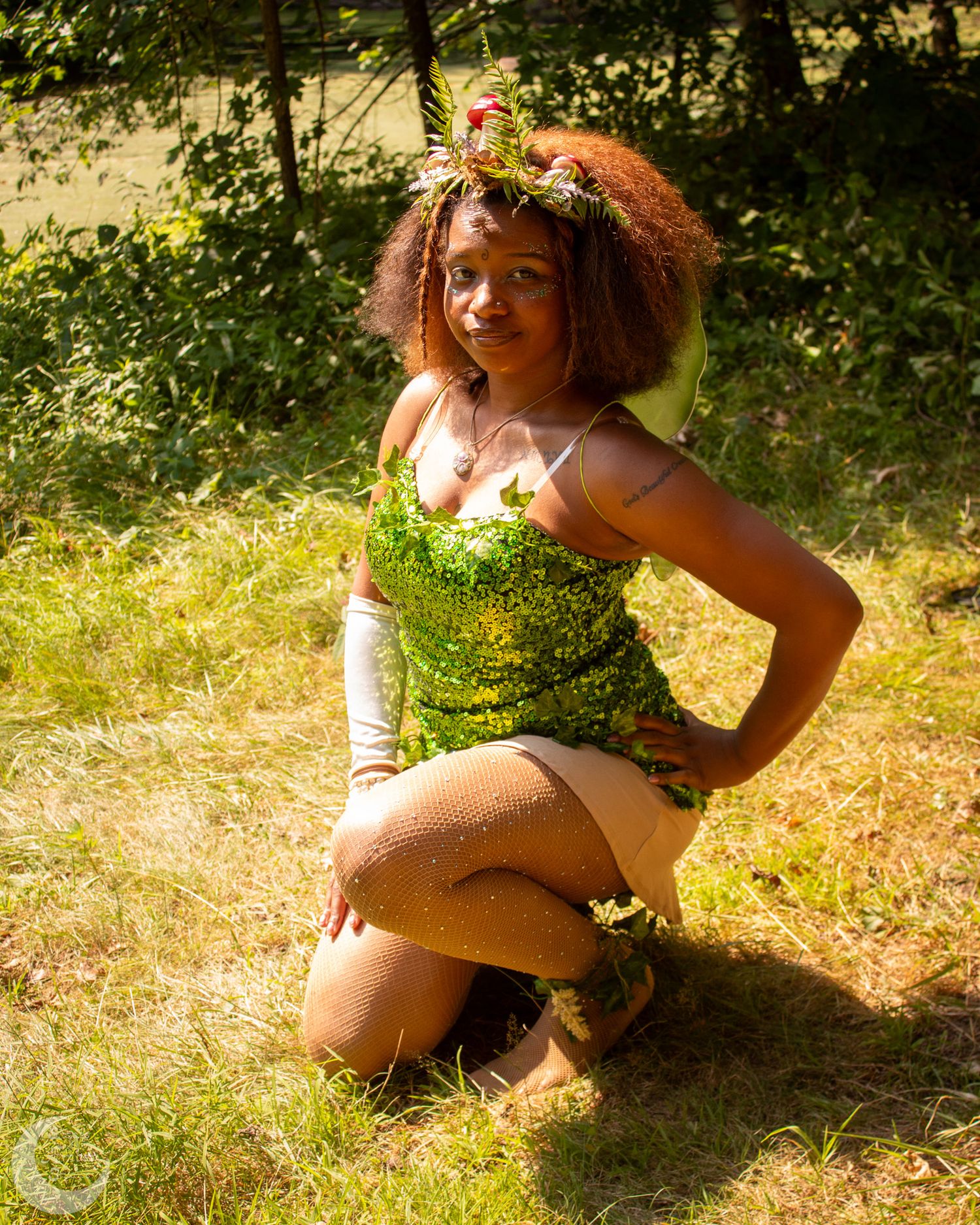Person in patterned outfit poses gracefully in sunny woodland setting during outdoor photoshoot.