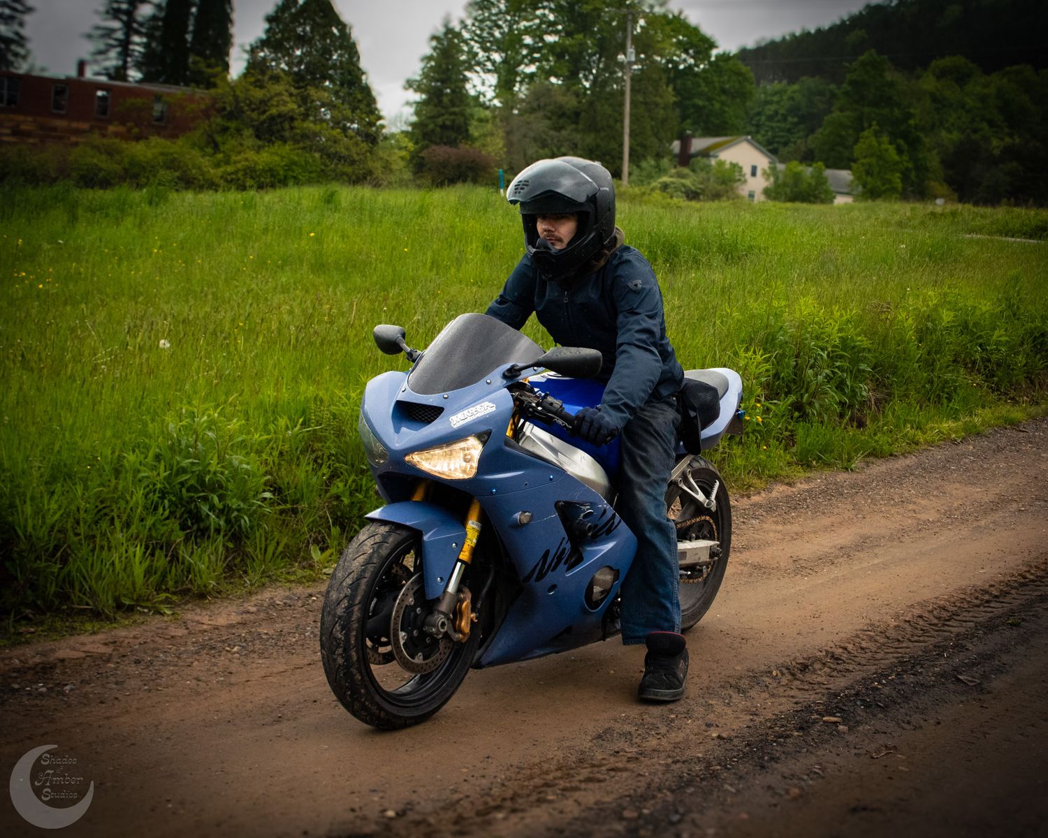 A series of motorcycle action shots showing a blue sport bike and rider navigating a dirt road through green countryside.