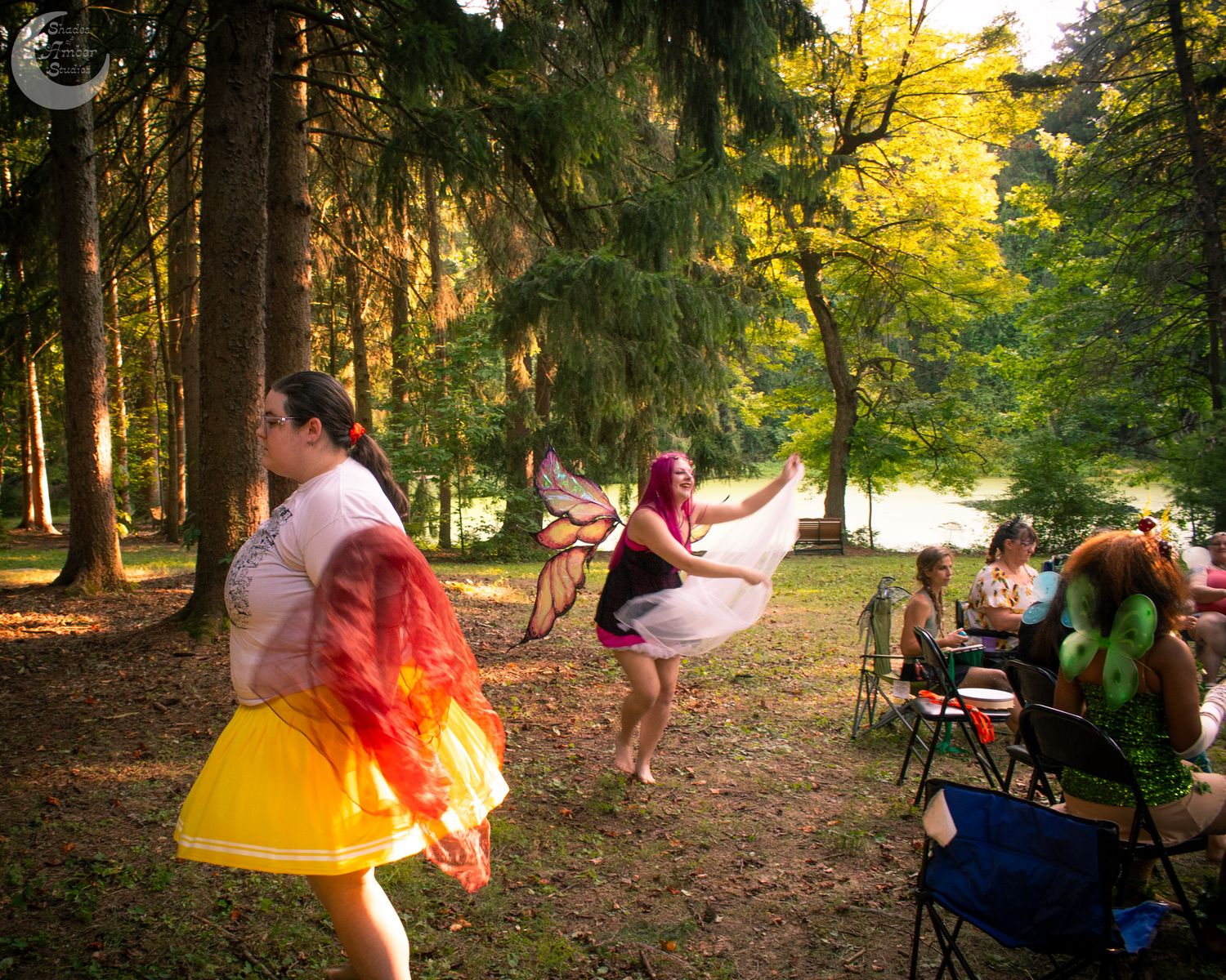 A magical woodland scene with dancing figures in colorful dresses illuminated by warm sunlight filtering through trees.