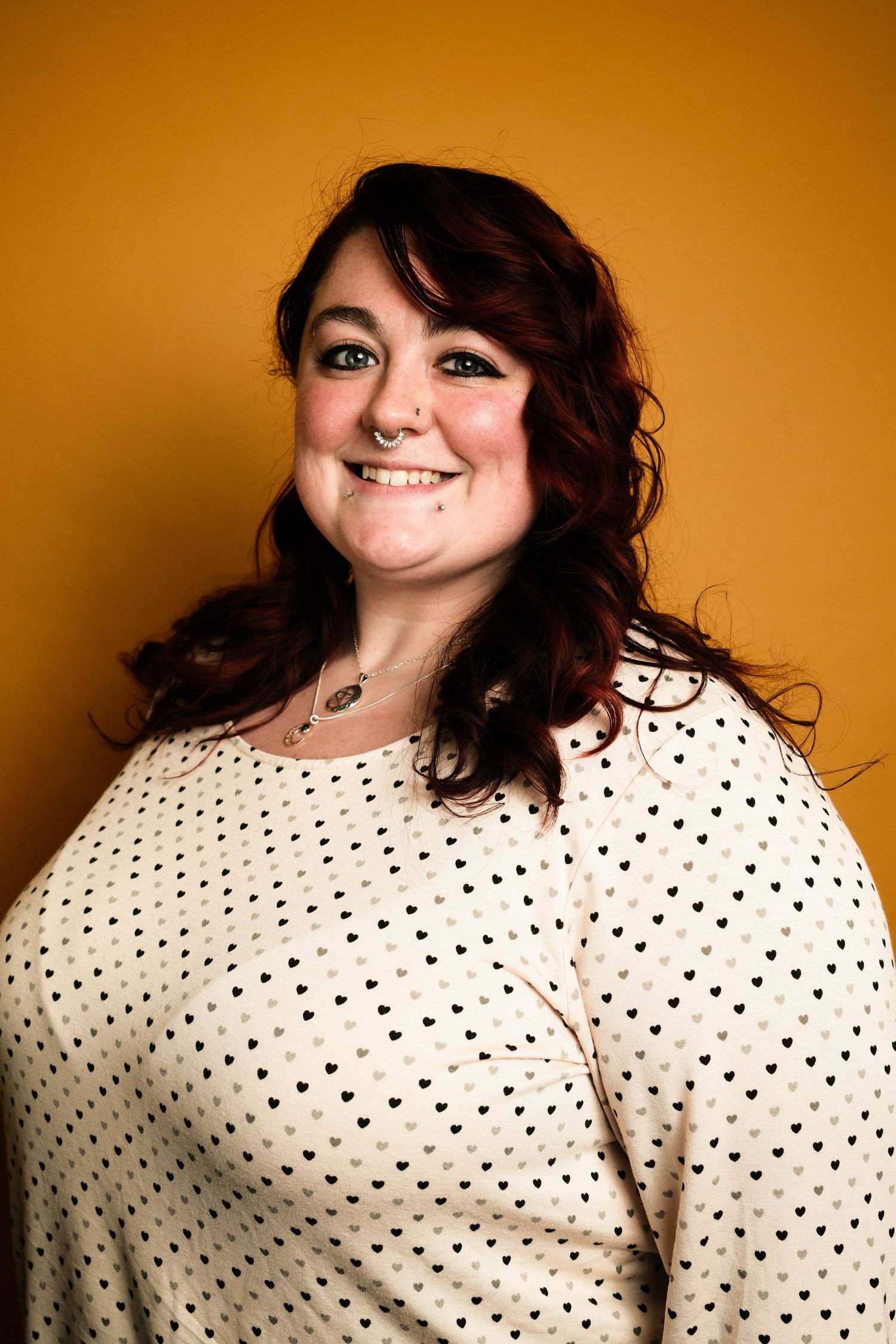 Person in polka dot sweater poses against orange background with playful expressions in photo series.