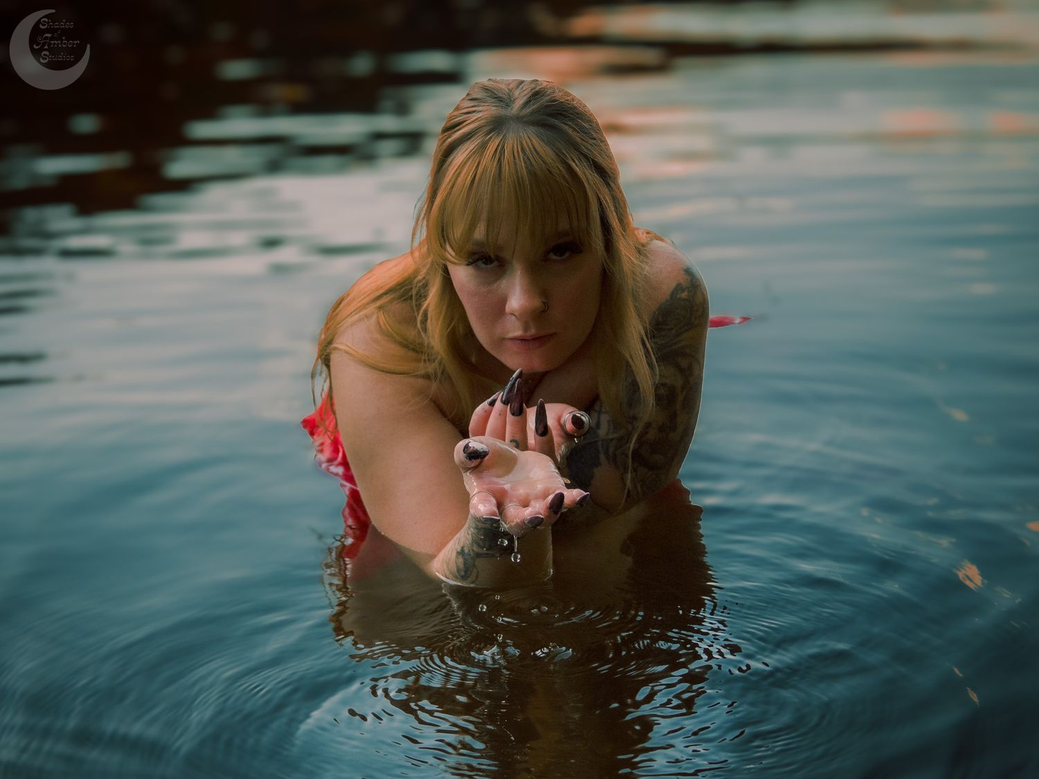 Figure in red swimwear floating in dark reflective water at dusk.