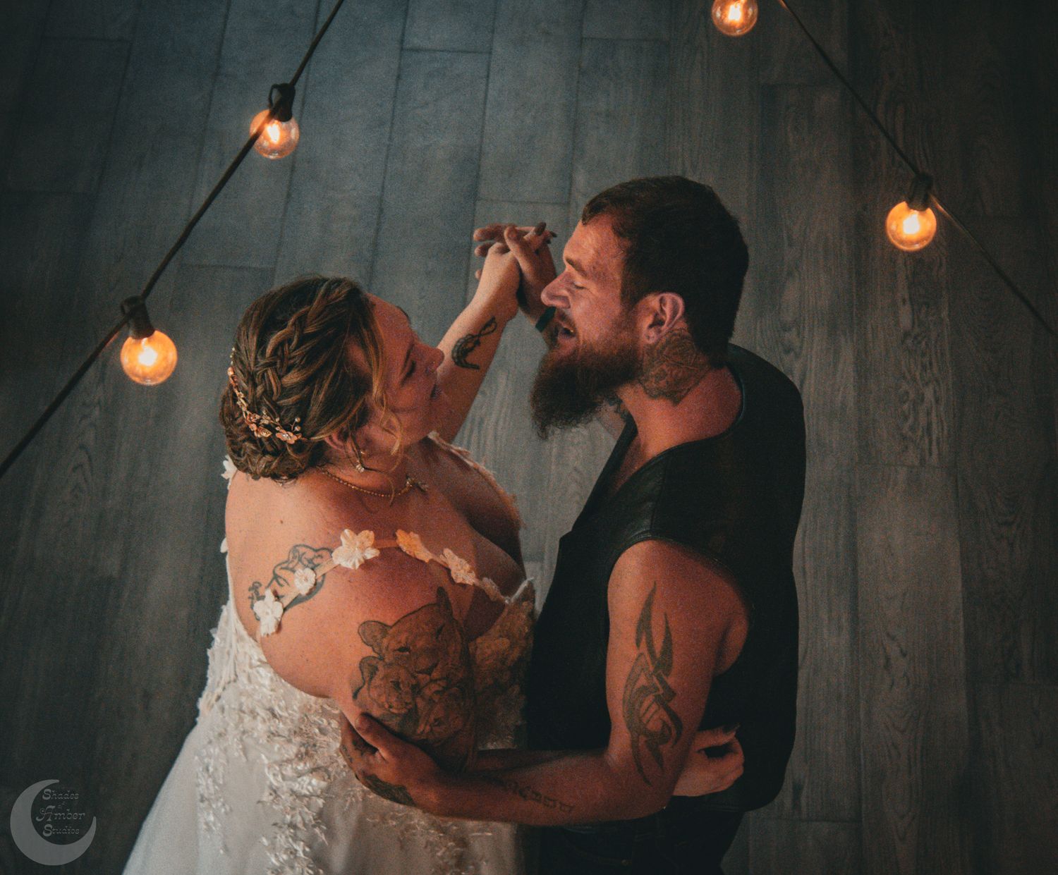 A tender dancing moment captured under warm string lights in an intimate indoor setting.