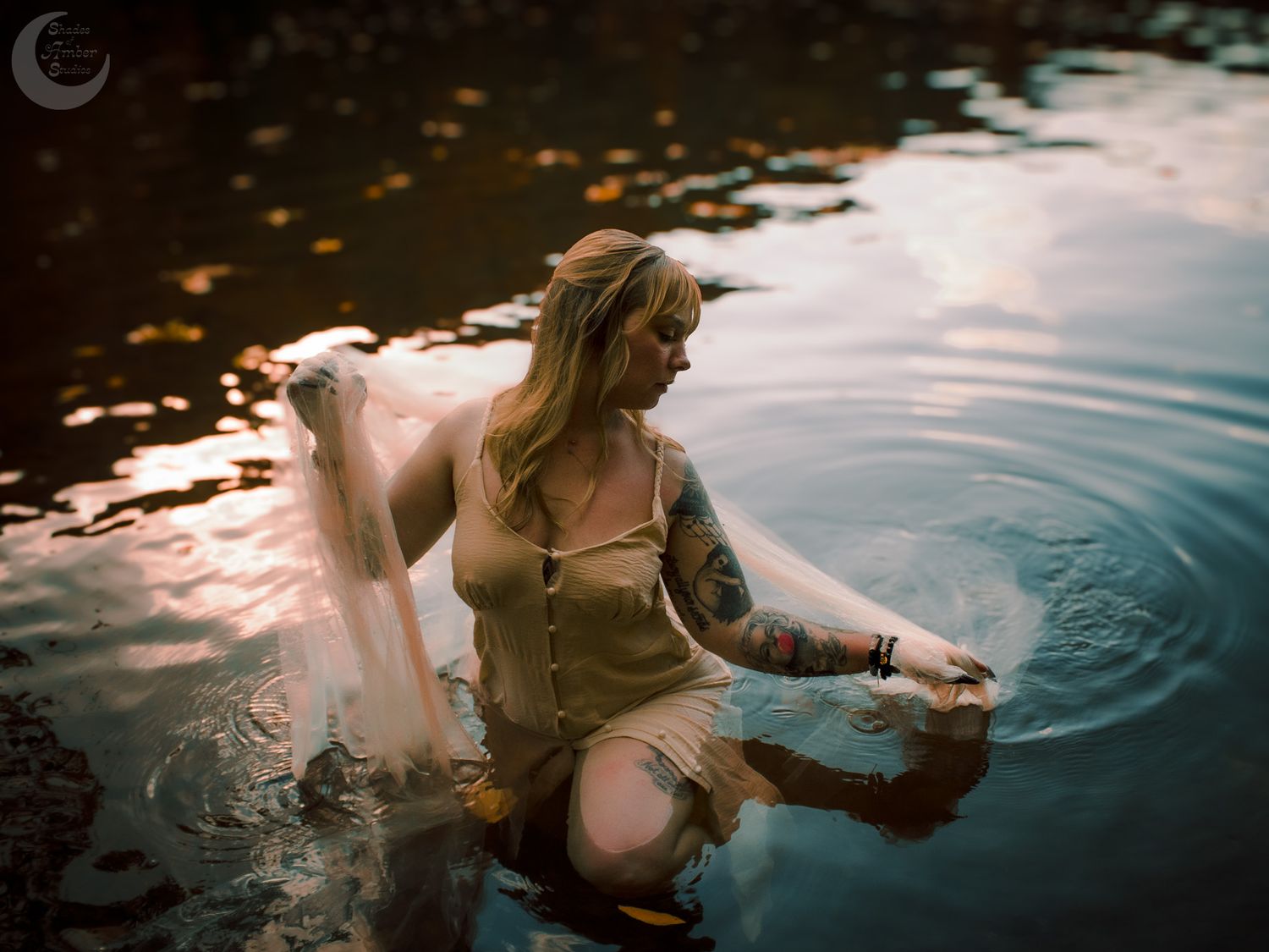 Artistic water portrait with flowing fabric creating ripples in dusky light.