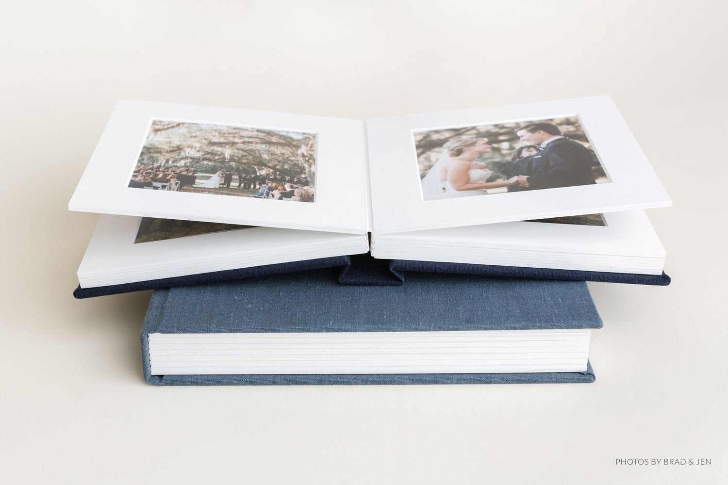 A navy blue photo album lies open displaying vintage black and white photographs on white pages.