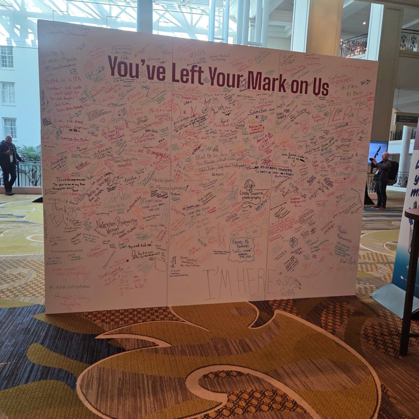A long white banner with signatures and messages hangs above curved wooden benches in an indoor space.