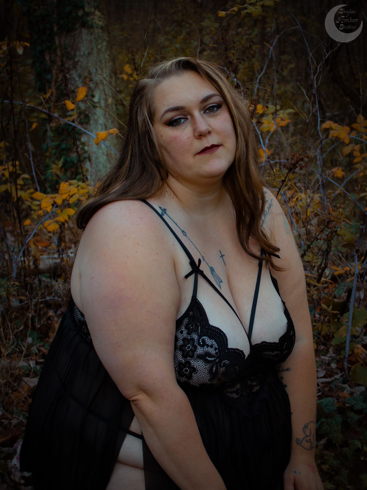 A moody autumn forest portrait featuring dramatic lighting and black lace fashion.