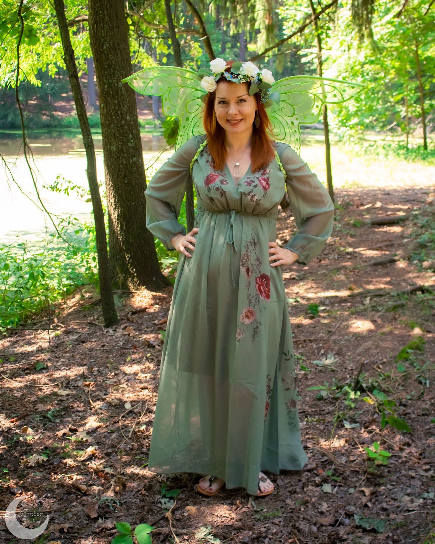 Someone in a vintage-style sage green dress explores a wooded forest setting on a sunny day.