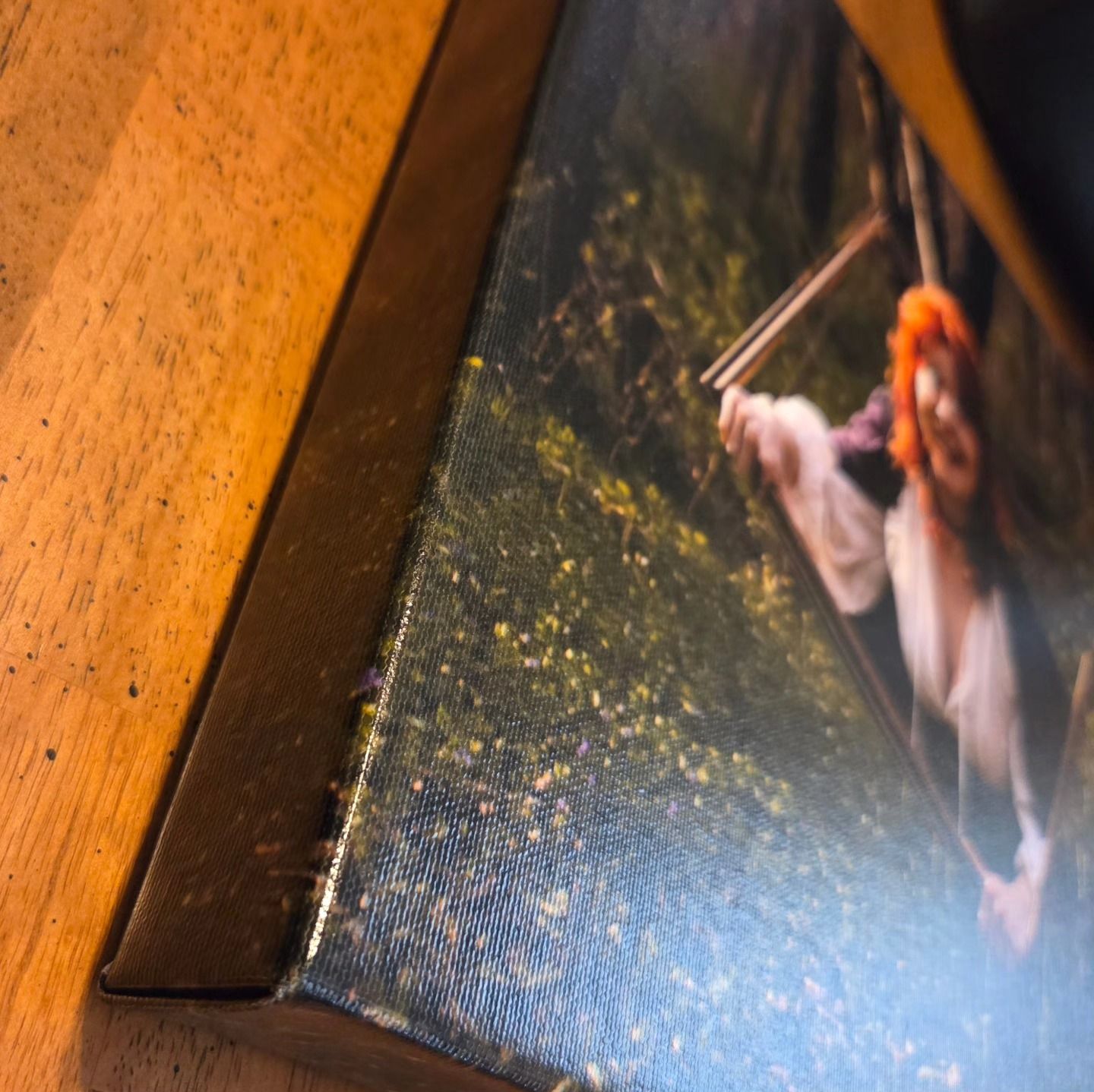 A person's hand flips the corner of a printed photograph against a dark wood table background.