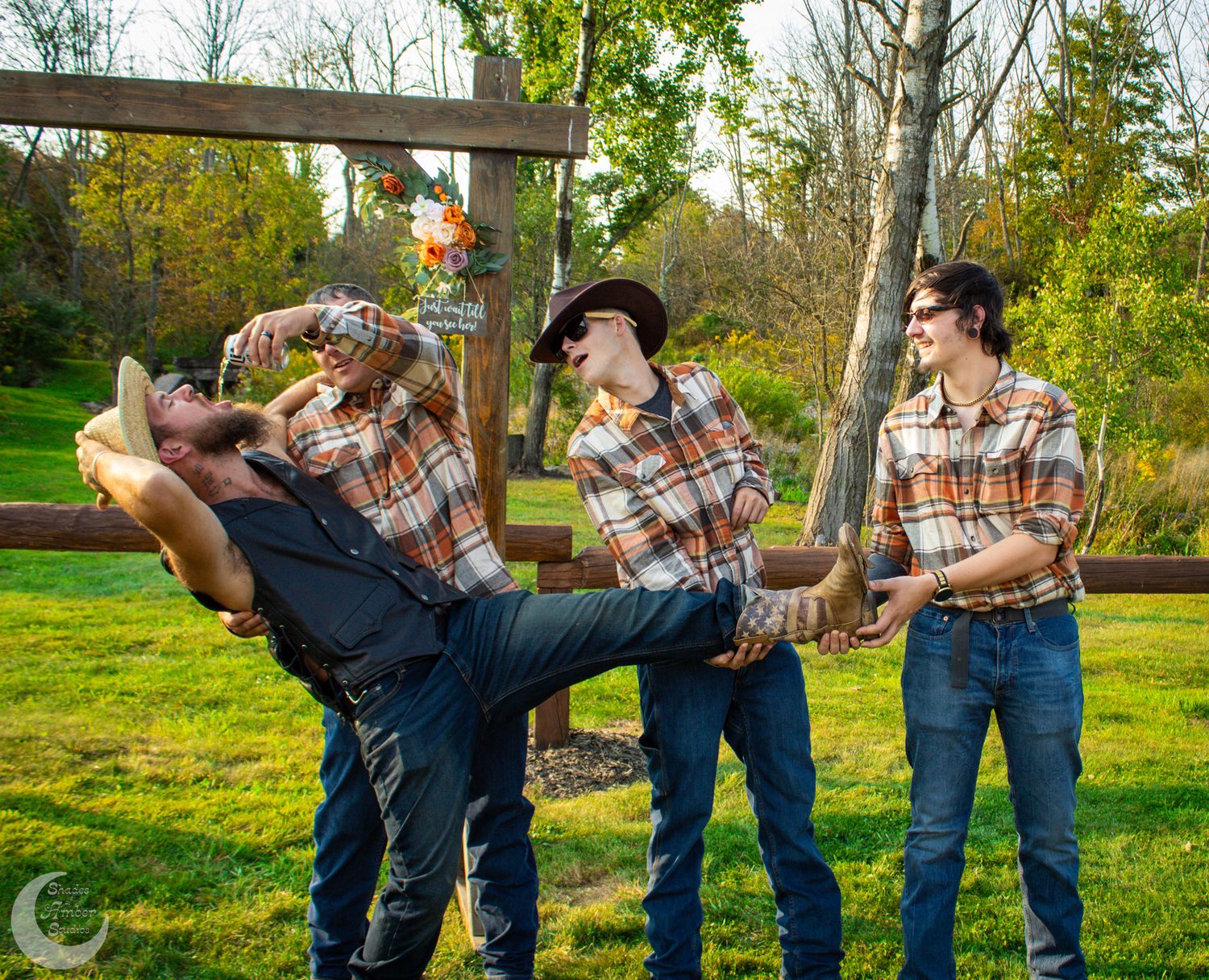 Playful group photo with matching plaid shirts during outdoor wedding celebration.