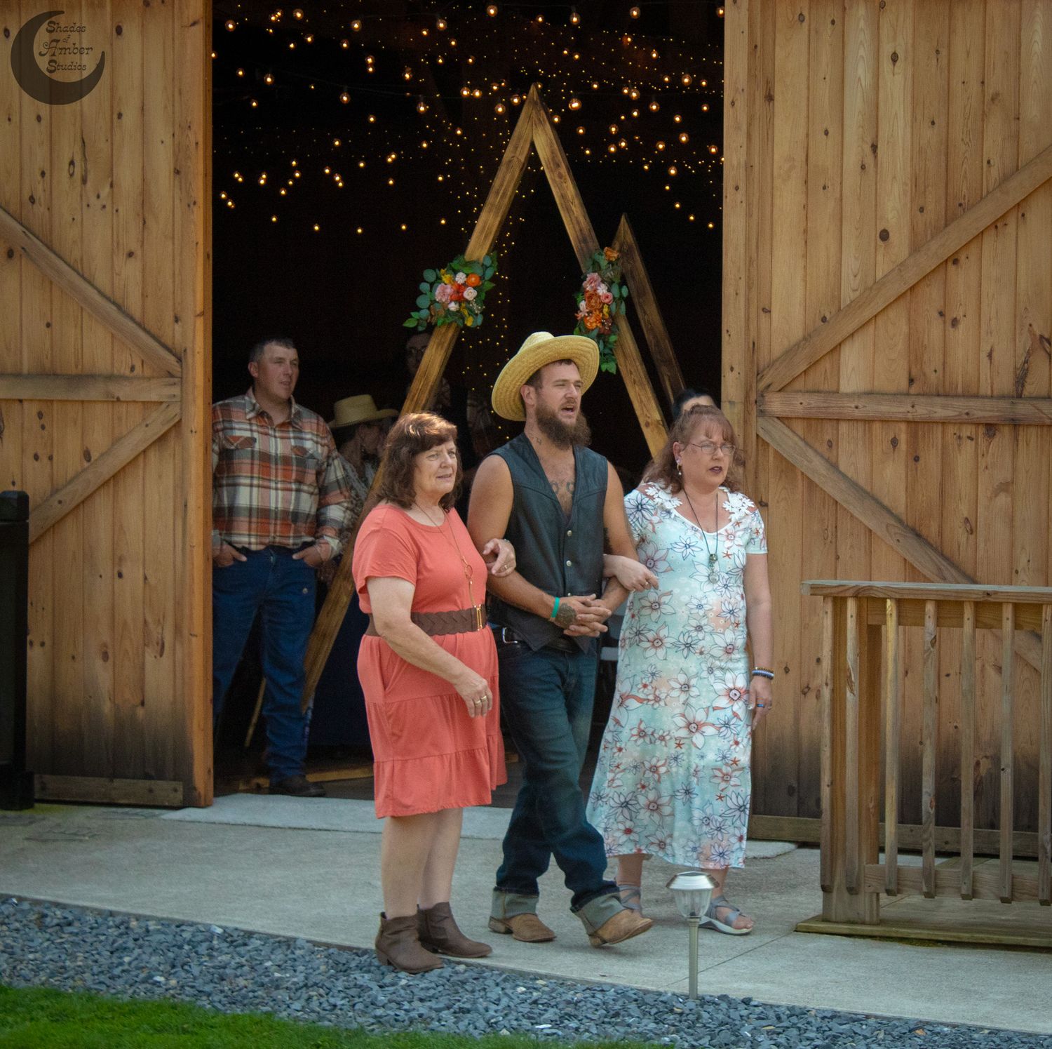 Rustic barn wedding scene with string lights and wooden triangle arch.