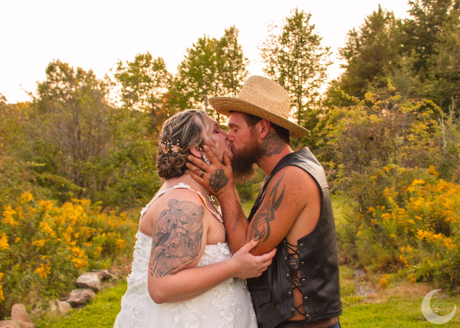 Romantic sunset wedding photo of couple embracing in field of golden wildflowers.