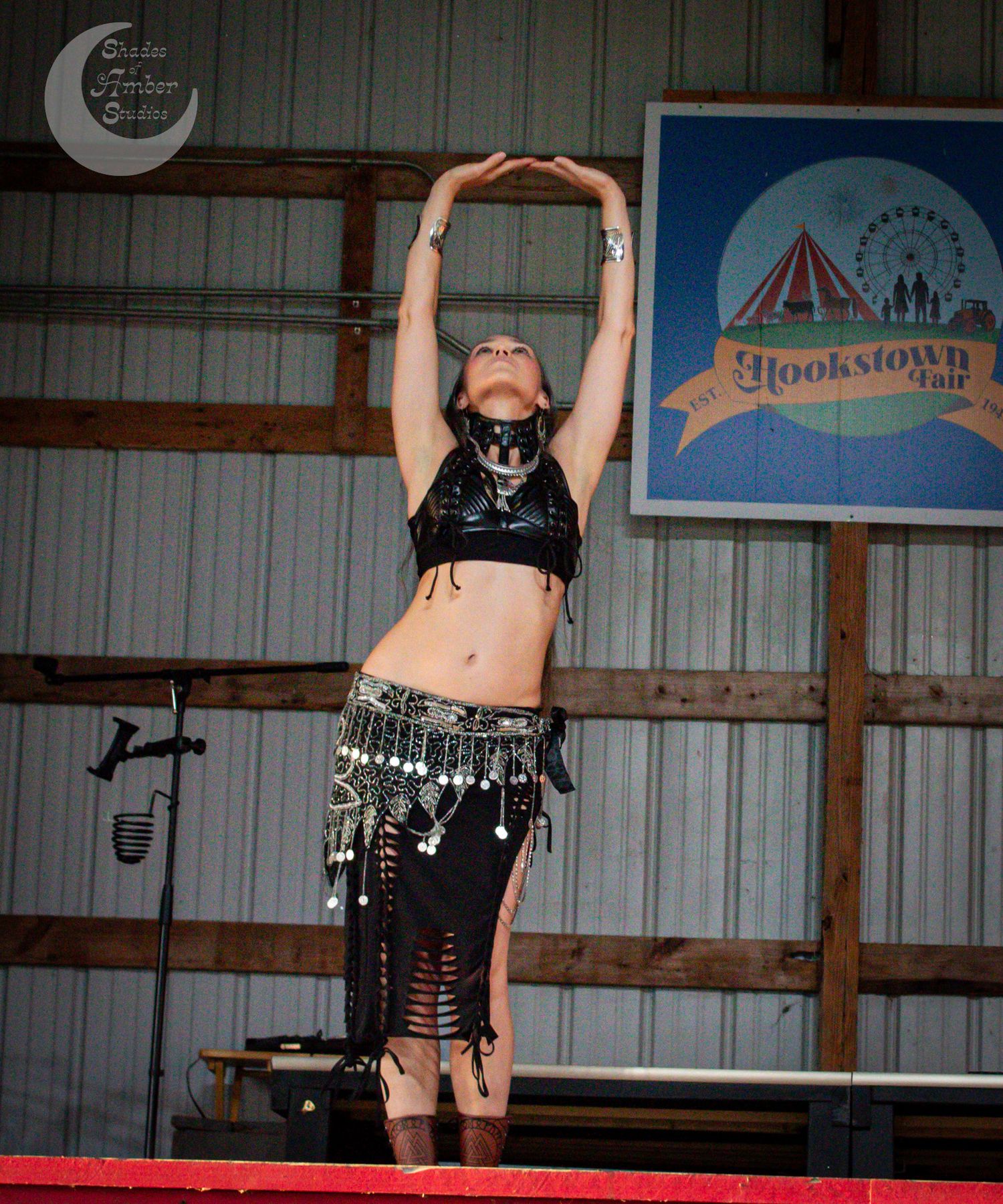 Performer in black attire demonstrates aerial dance moves on suspended equipment in an indoor studio space.