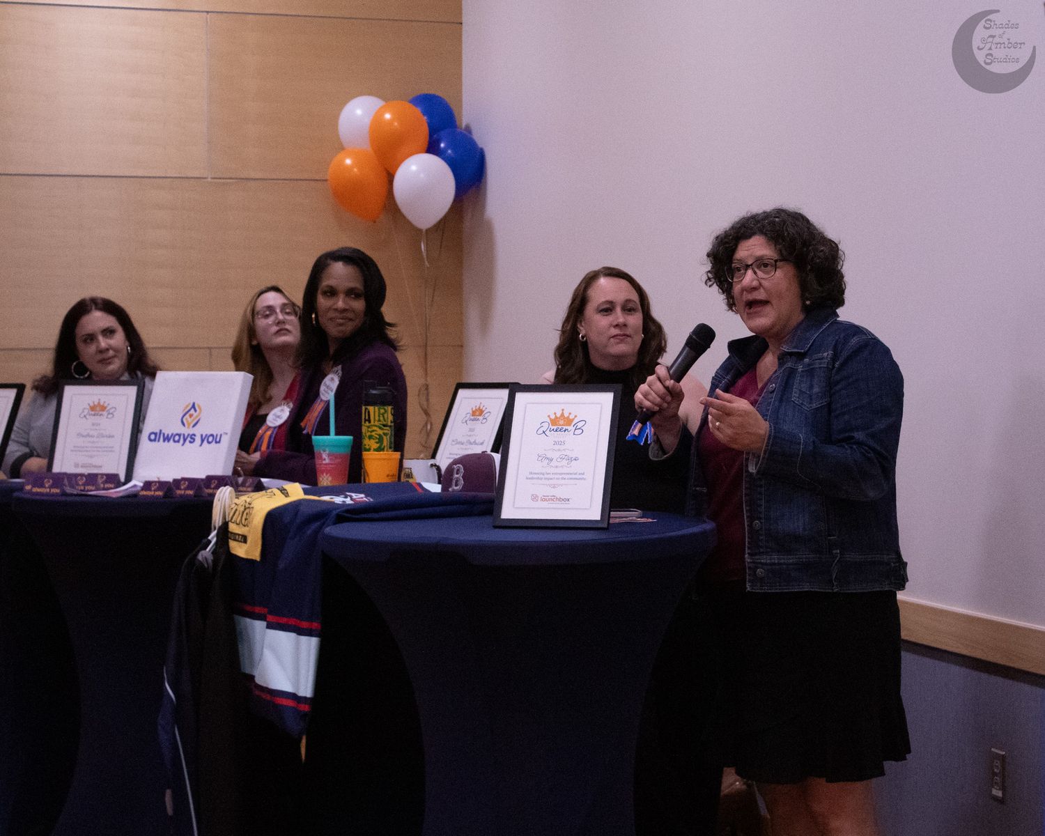 A panel discussion setup with speakers at a table with orange and blue balloons decorating the event space.