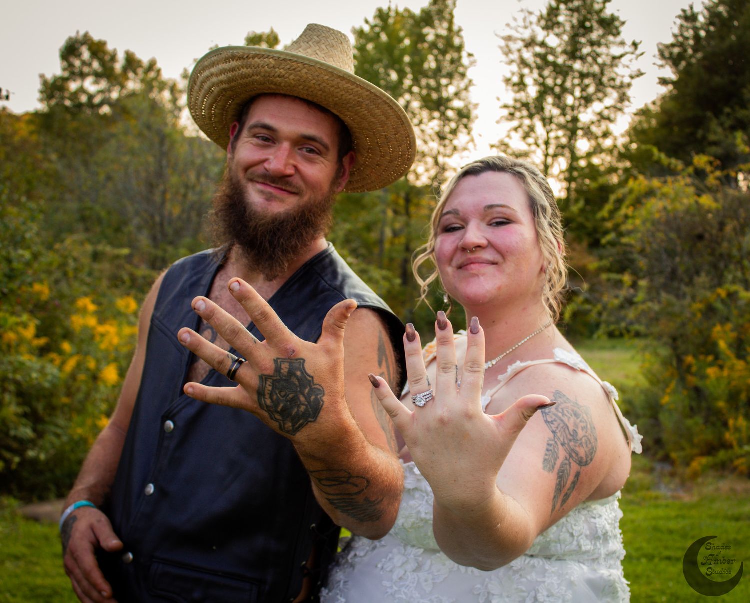 A joyful wedding couple showing off their rings in a garden setting.