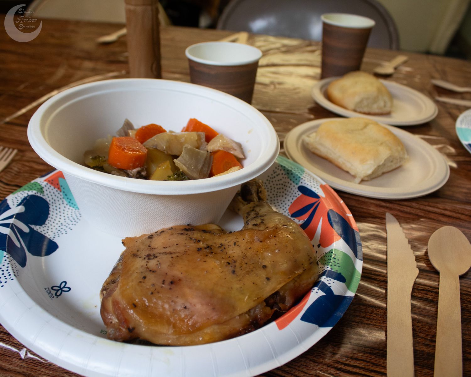 A panoramic view of multiple bowls and plates with soup, entrees, and sandwiches served on a wooden restaurant table.
