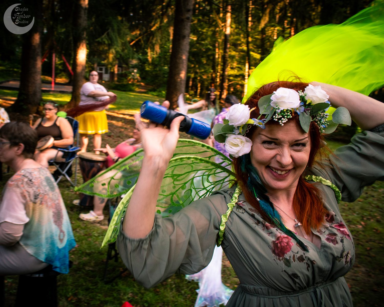 A festive woodland gathering with dancers and performers in fairy-themed costumes.