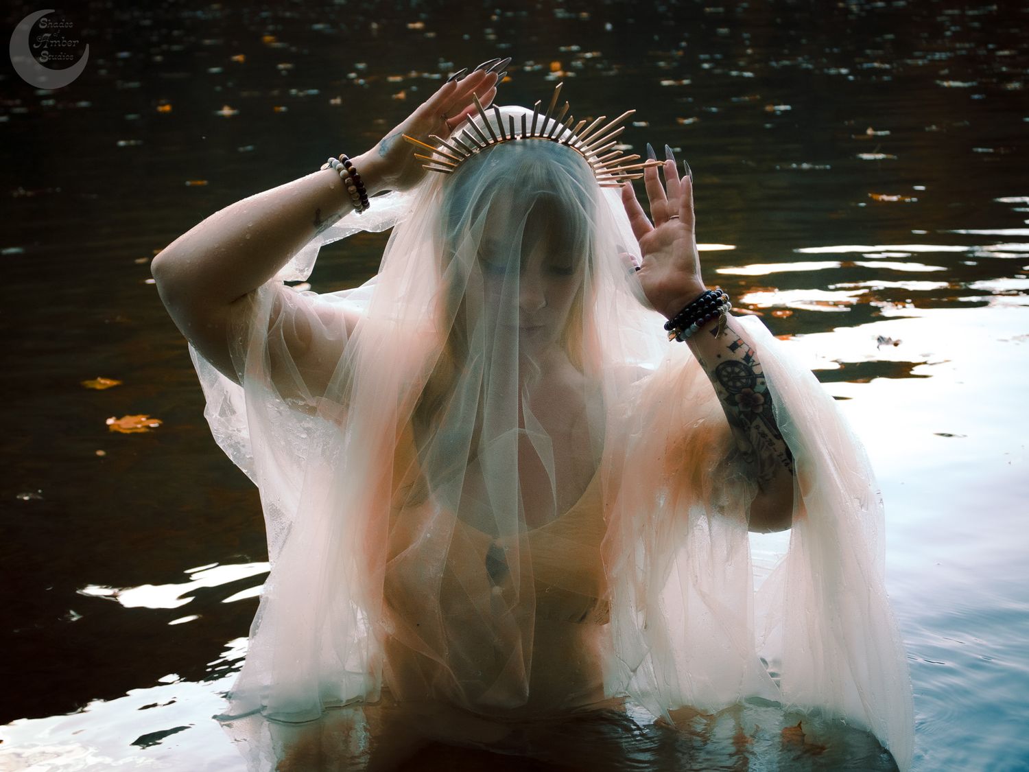 Mysterious figure wearing a crown emerges from dark water with ethereal veil effects.
