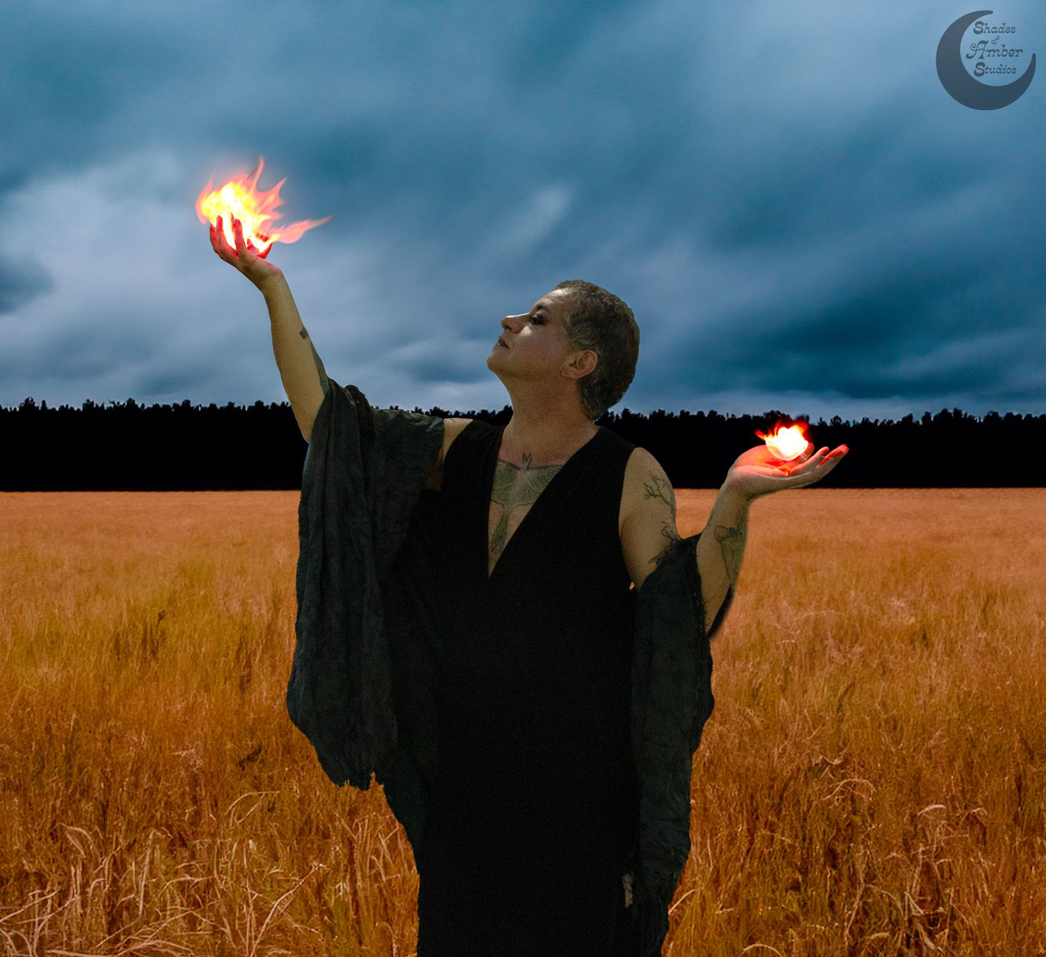 Person in black cloak holding fire in both hands while standing in wheat field at dusk.