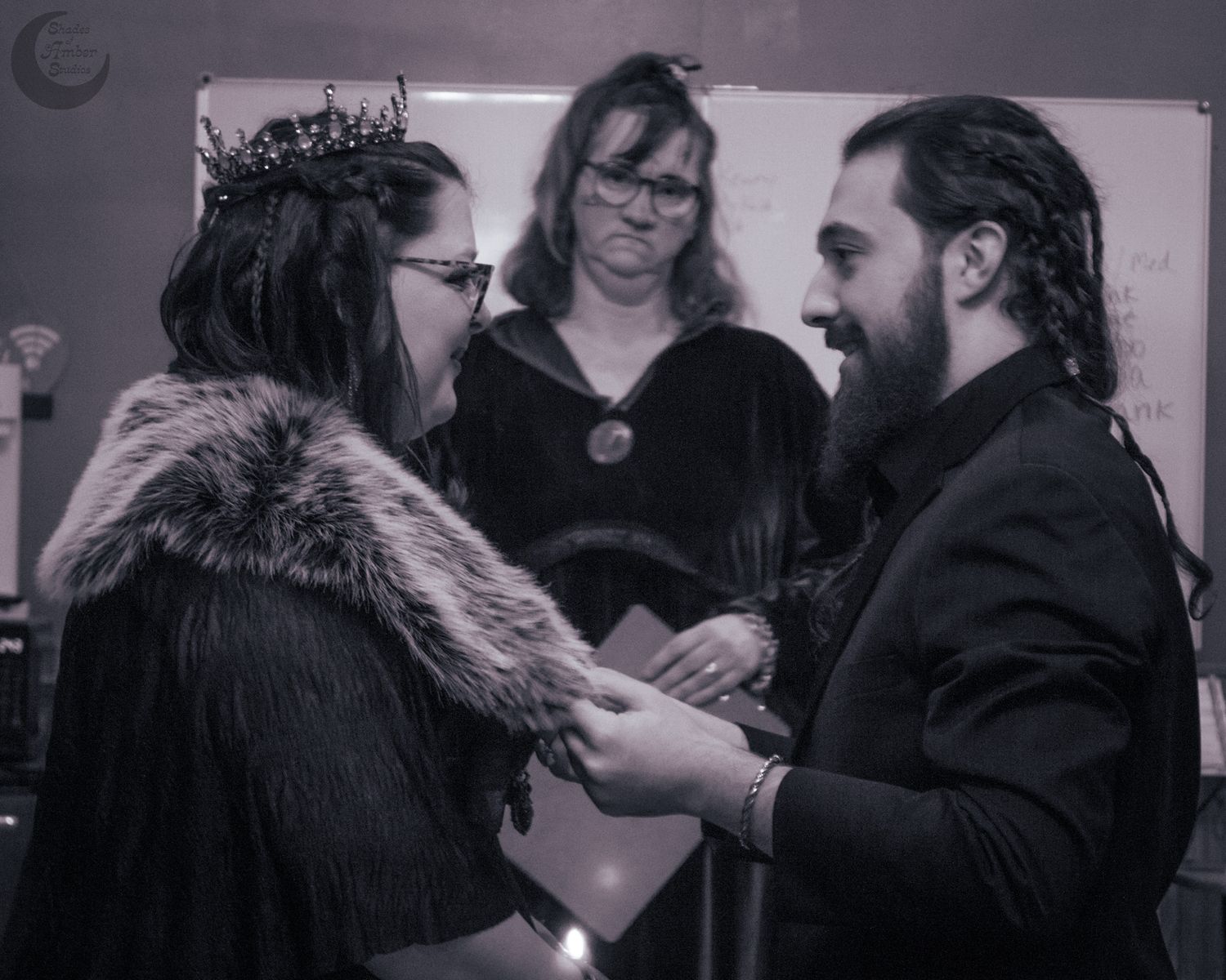 An intimate handfasting ceremony in black and white showing hands being bound together.