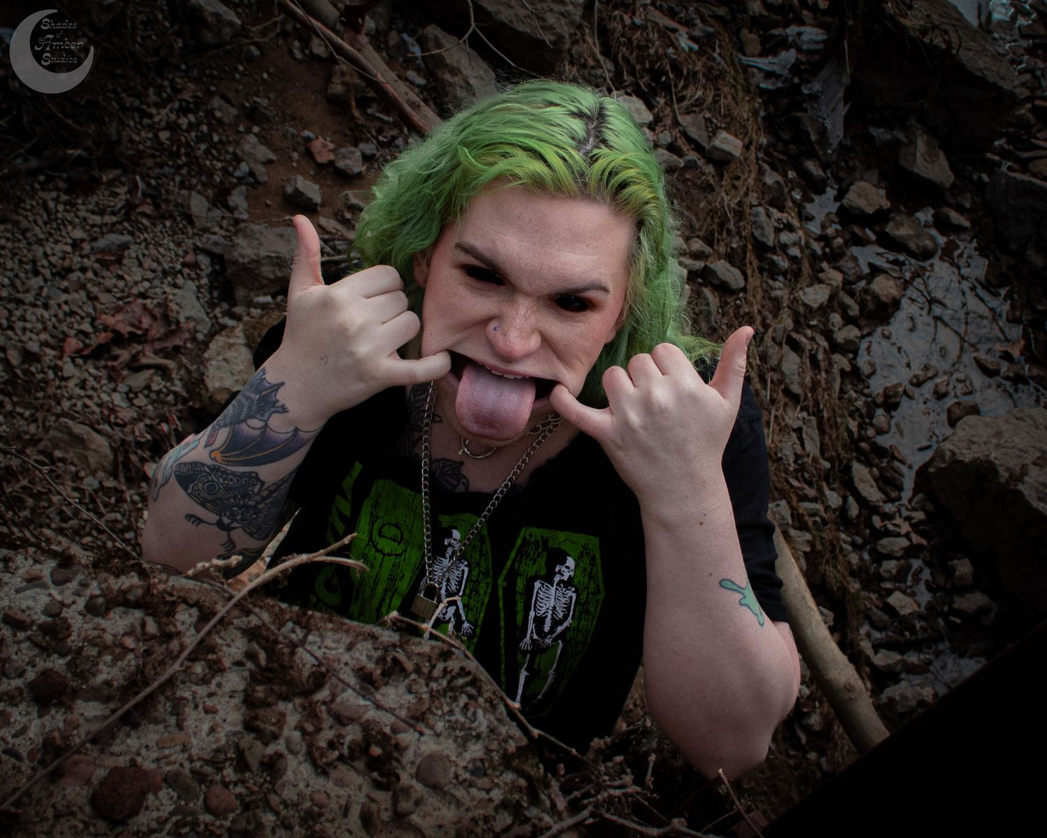 Rock-style portrait with green hair making hand gestures against earthy background.