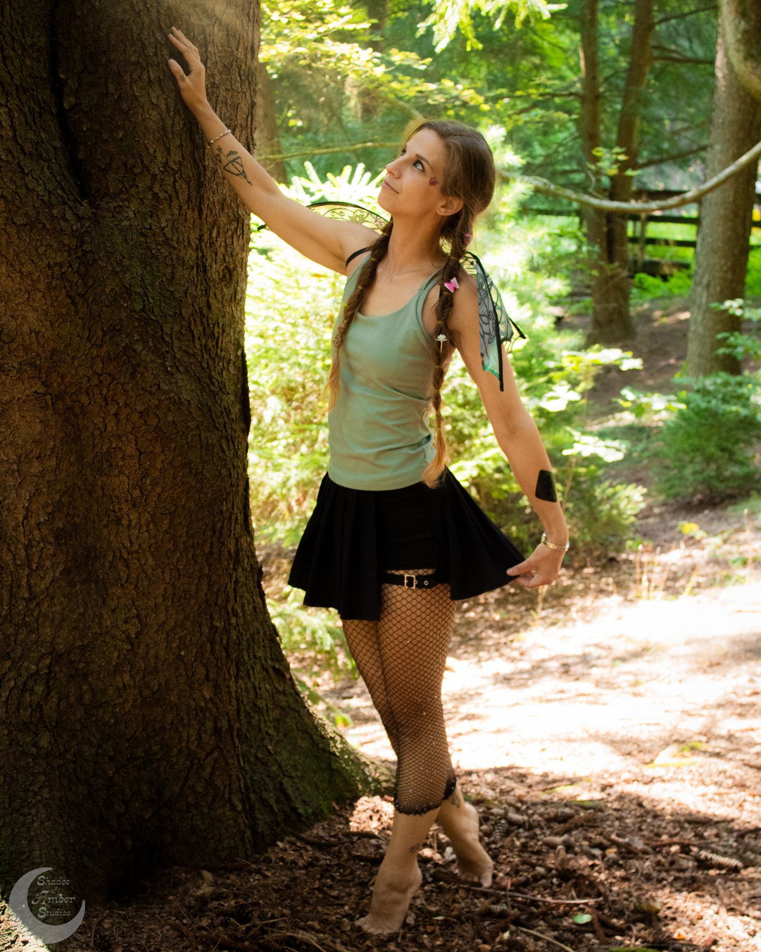 Playful poses captured between large tree trunks in dappled forest light.
