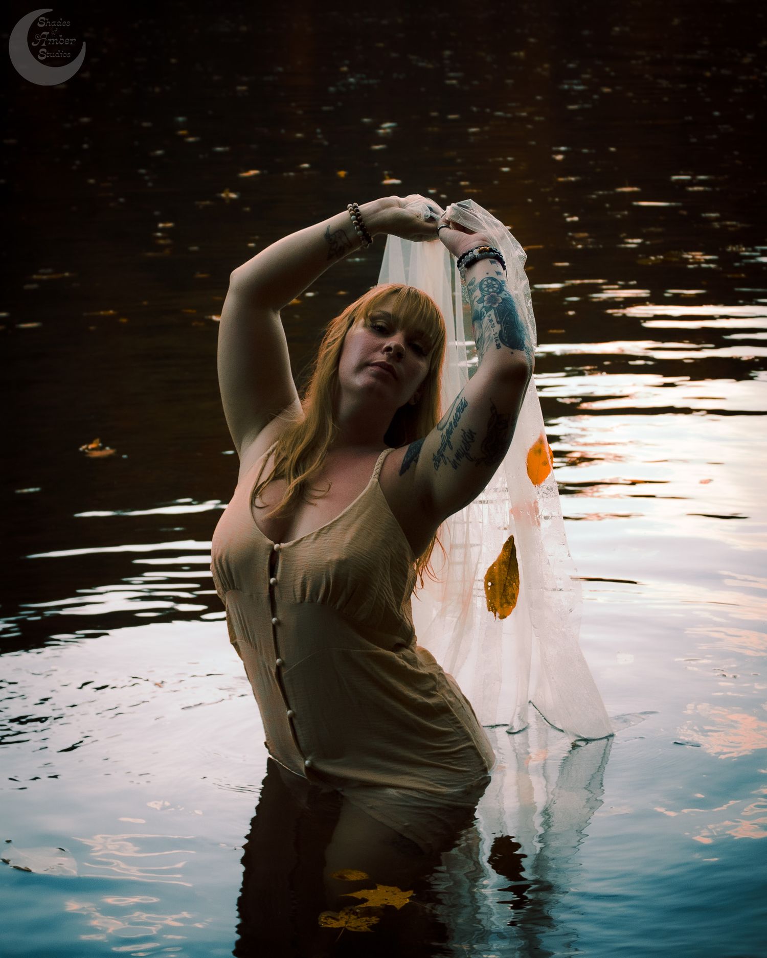 Ethereal water dance scene with flowing fabric and autumn leaves at sunset.