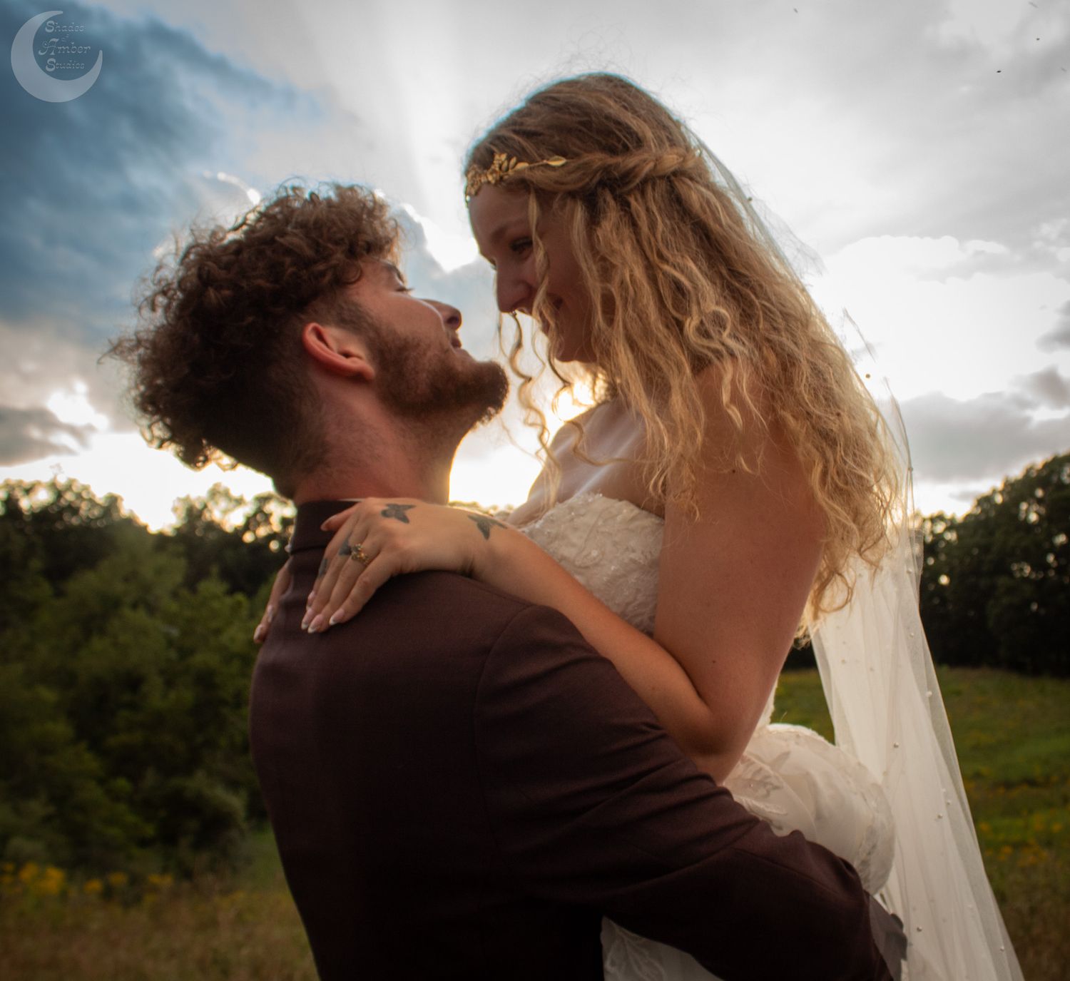 Romantic wedding couple embracing during golden hour sunset in an outdoor setting.